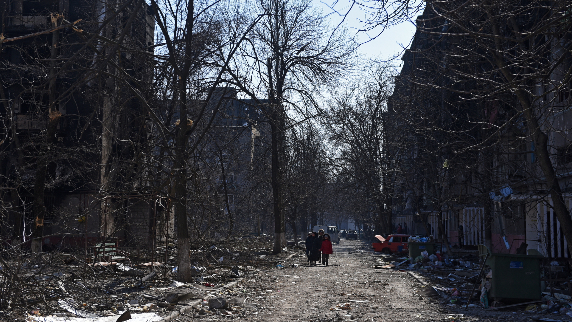Menschen gehen zwischen zerstörten Wohnhäusern in Mariupol (Archivbild vom 18.3.2022) | REUTERS