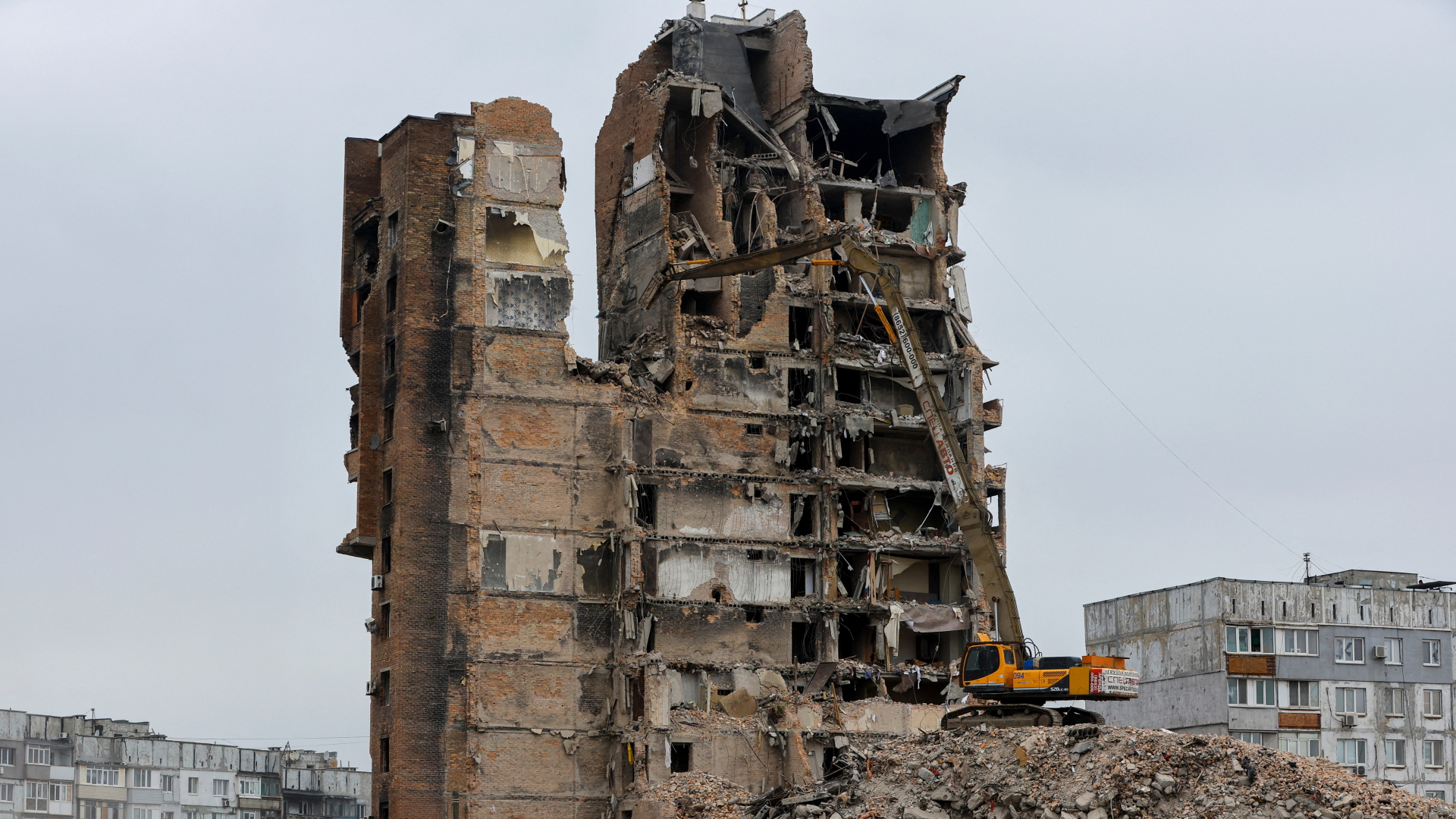 Ein Bagger auf einem Schuttberg reißt ein zerstörtes Hochhaus im russisch besetzten Mariupol ab (Aufnahme vom 16. März 2023) | REUTERS