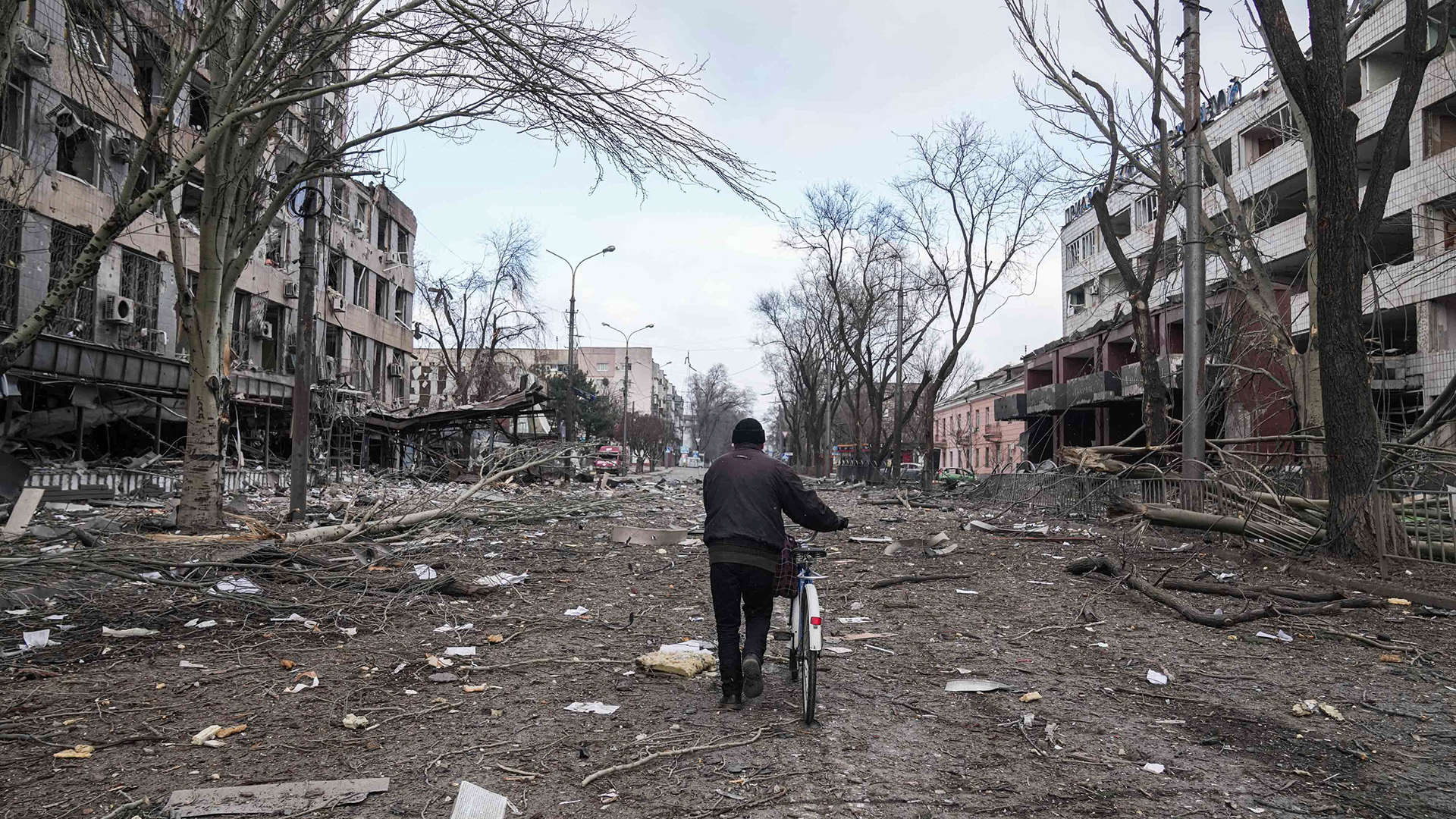 Ein Mann schiebt sein Fahrrad durch das zerstörte Mariupol. | picture alliance/dpa/AP