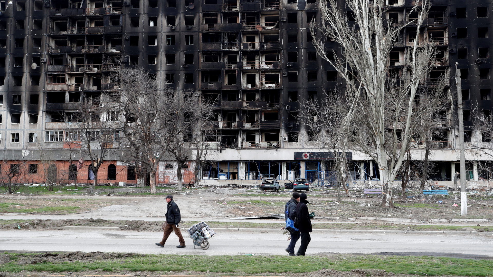 Menschen vor einem ausgebrannten Gebäude in Mariupol | REUTERS