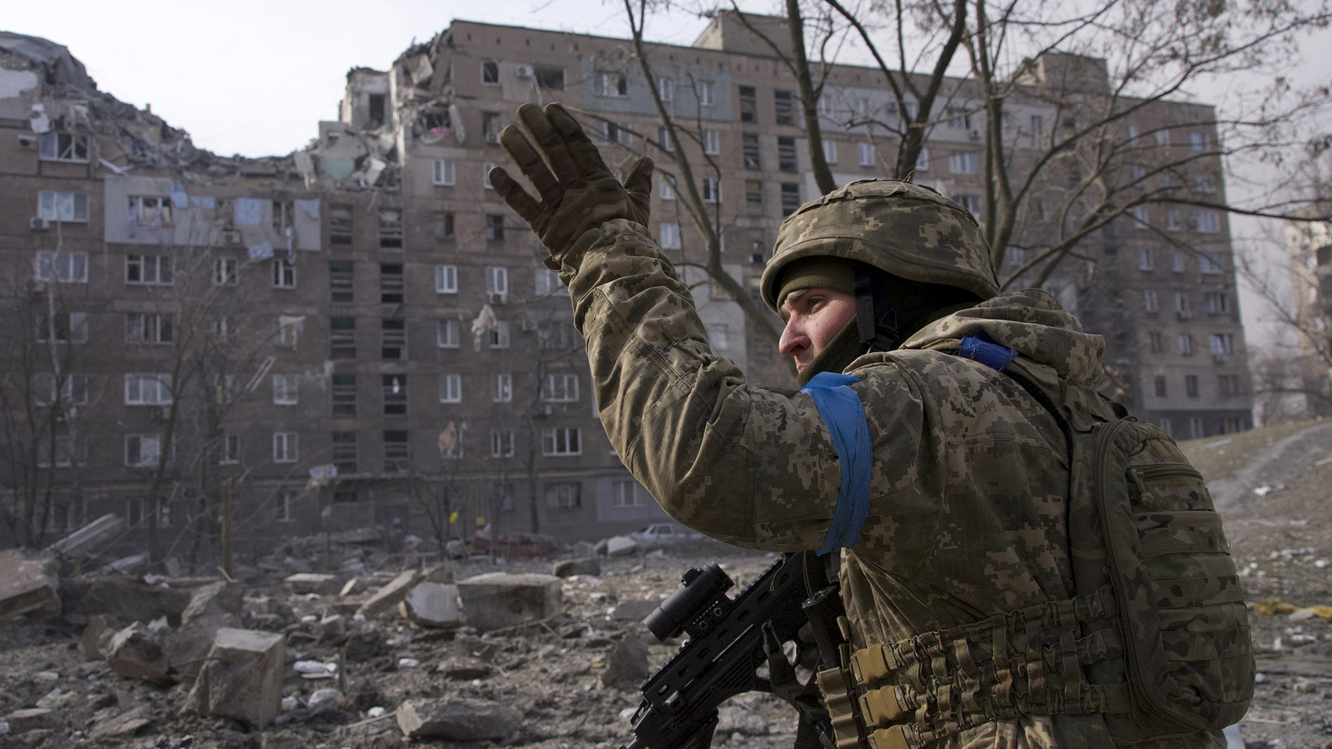 Ein ukrainischer Soldat steht vor zerstörten Häusern in Mariupol (Archivbild vom 12.03.22). | AP