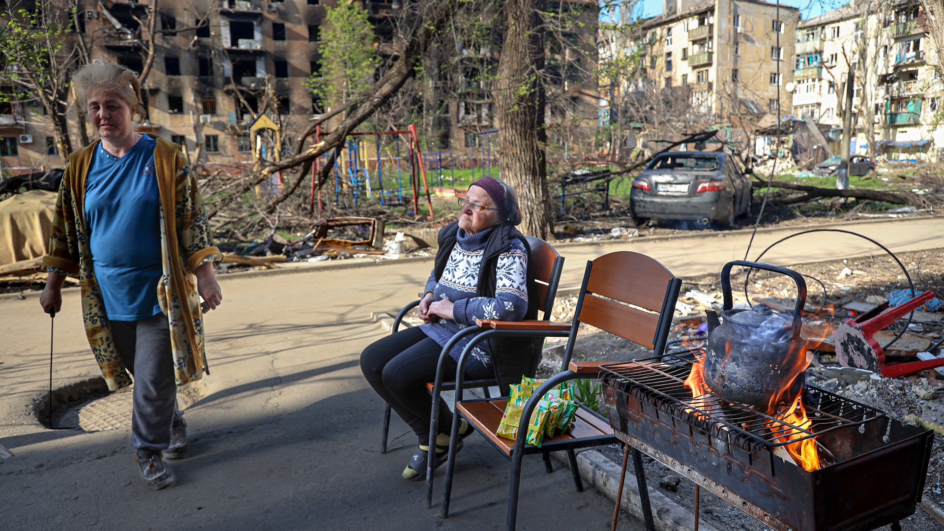 Eine Frau sitzt in Mariupol vor ausgebrannten Wohnhäusern auf einem Stuhl. | AP
