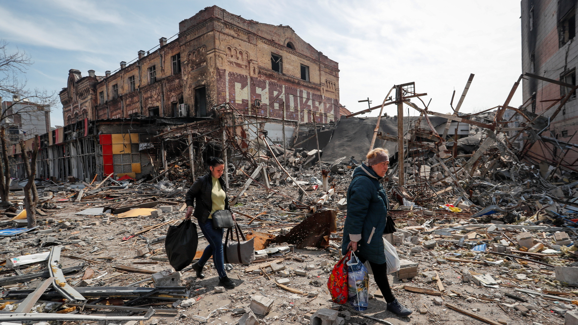 Menschen tragen ihr Hab und Gut in der zerstörten ukrainischen Hafenstadt Mariupol. | REUTERS