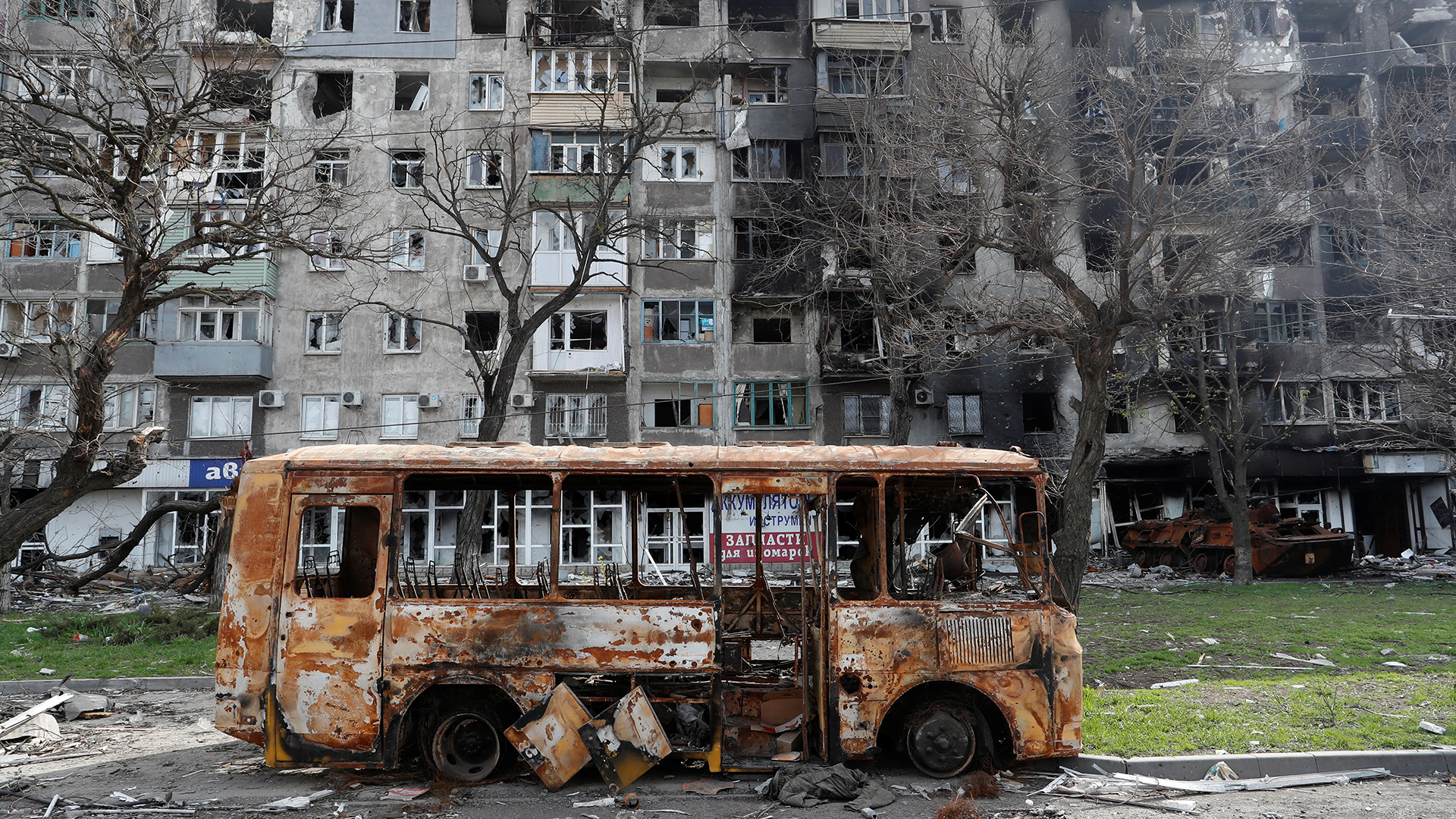 Ein ausgebrannter Bus steht vor einem zerstörten Wohngebäude in Mariupol. | REUTERS