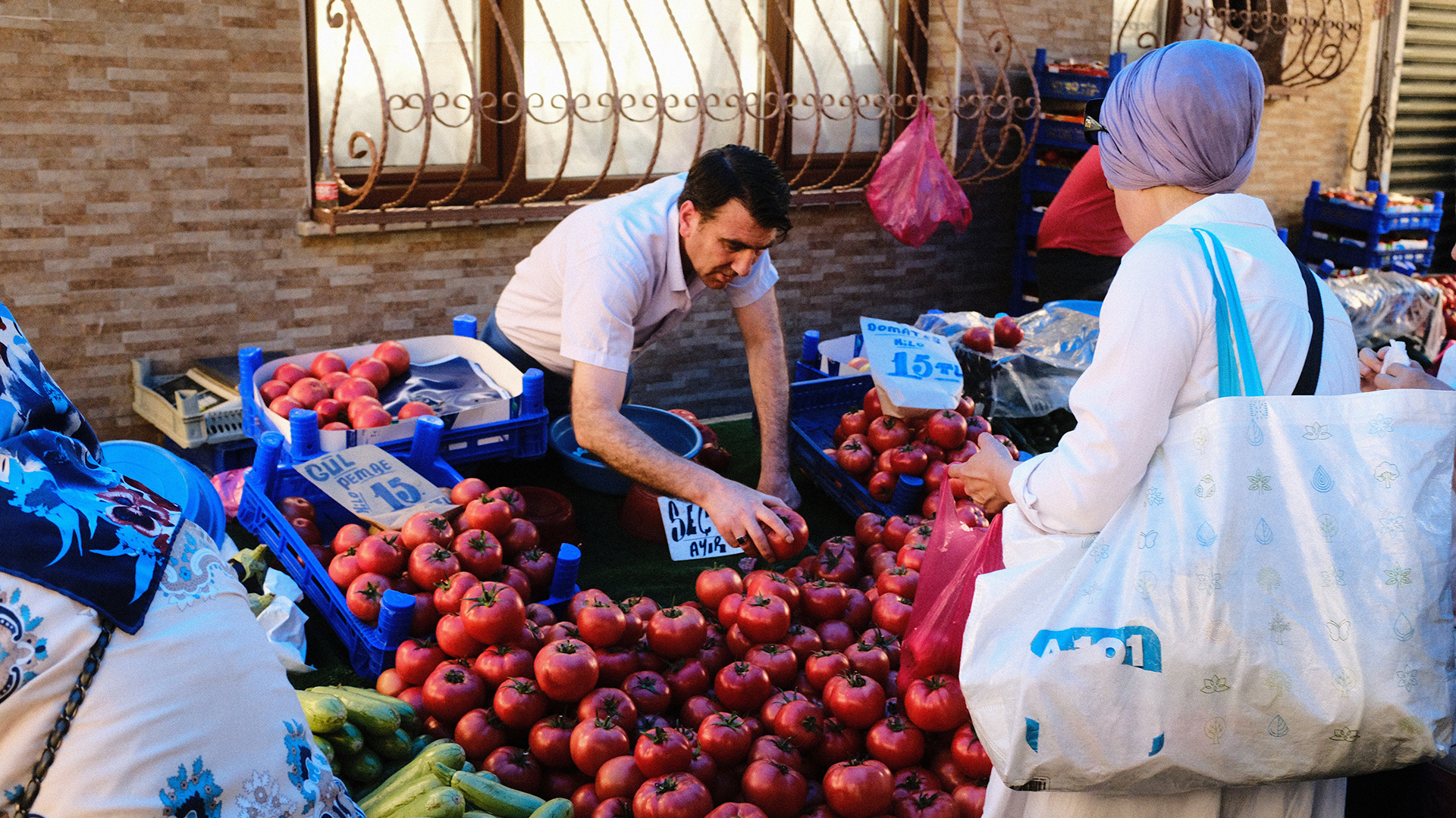 Ein Mann verkauft auf einem Markt Tomaten - eine Kundin steht an seinem Stand | picture alliance / NurPhoto