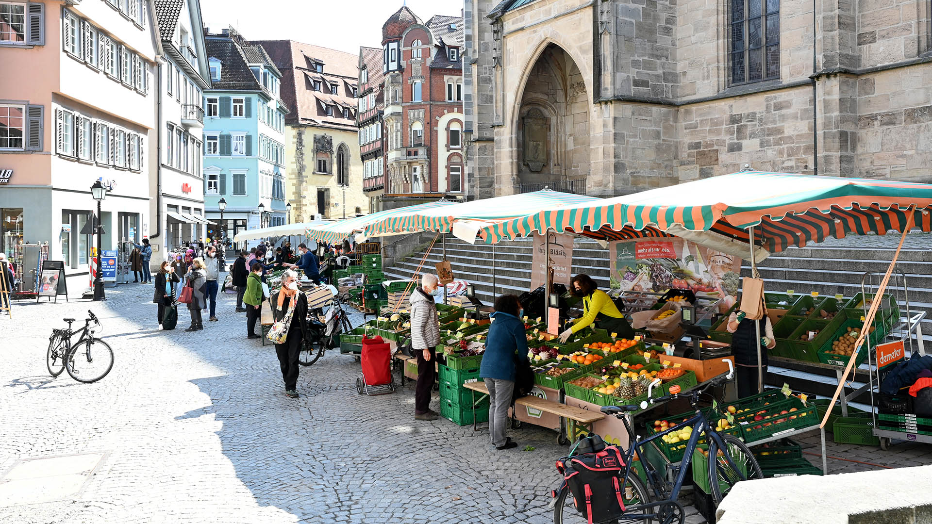 Passanten gehen in der Fußgängerzone an Marktständen in Tübingen vorbei.  | dpa