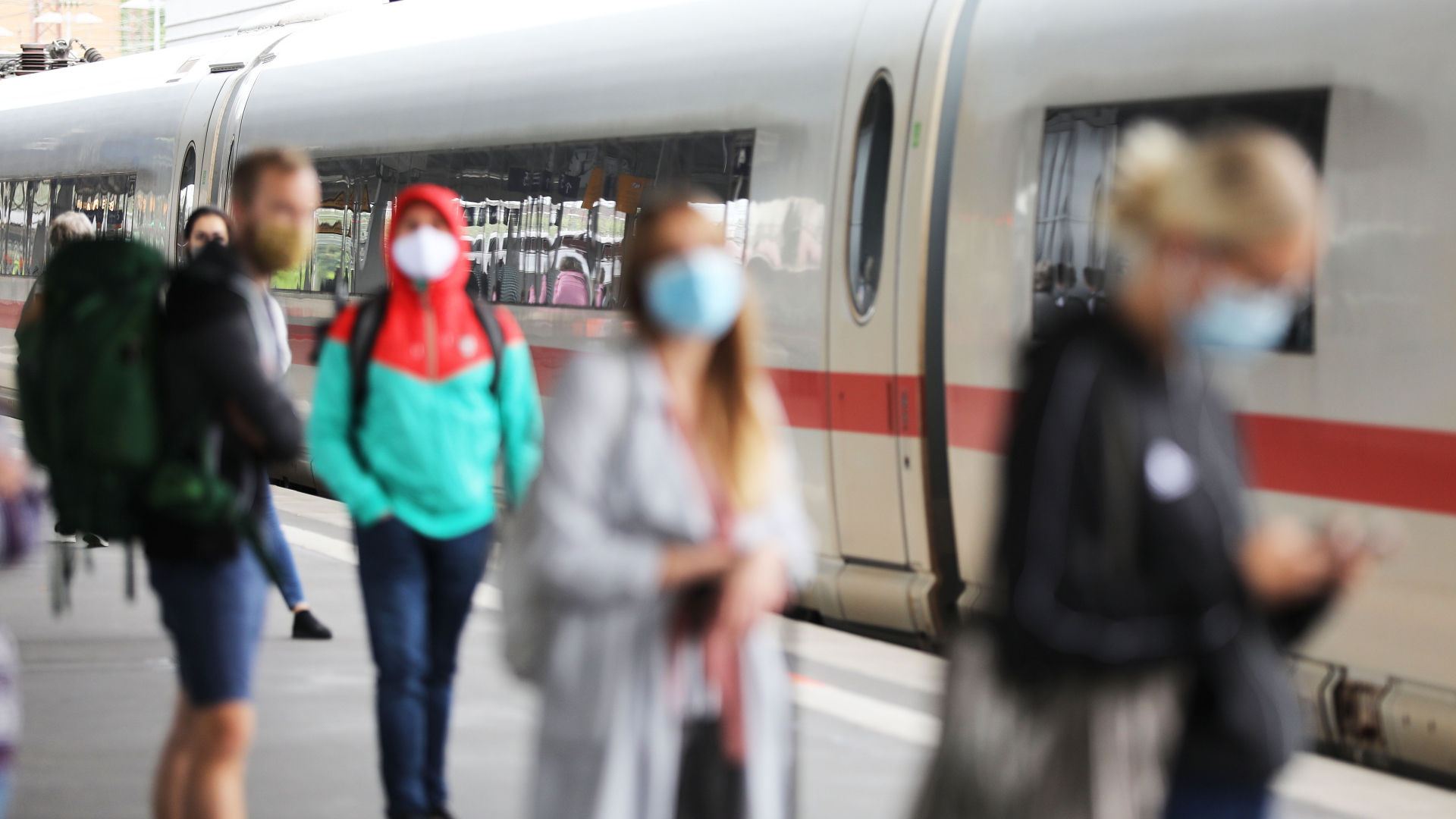 Reisende stehen auf dem Essener Hauptbahnhof mit Masken an einem Zug. | dpa