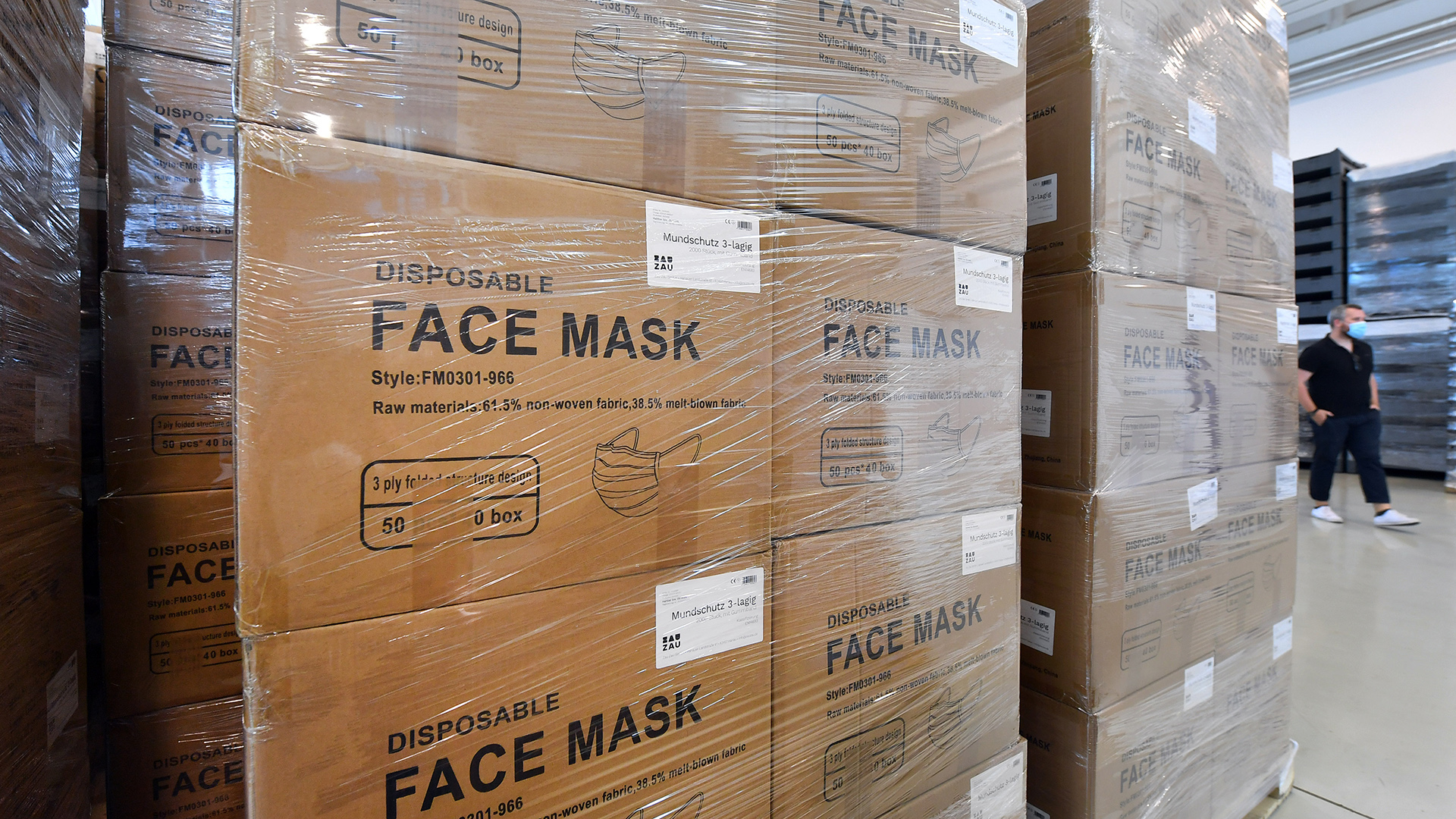 Paletten voller Kartons mit Gesichtsmasken stehen in einem Lager.