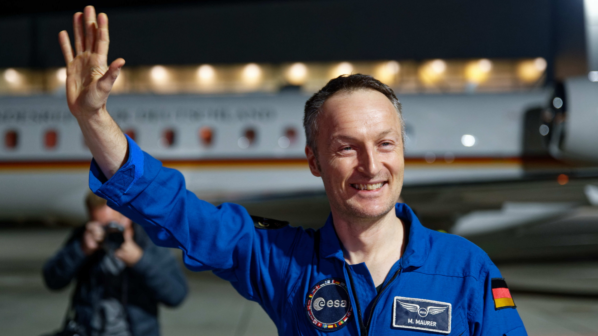 Astronaut Matthias Maurer winkt bei seiner Ankunft am Flughafen Köln/Bonn.
