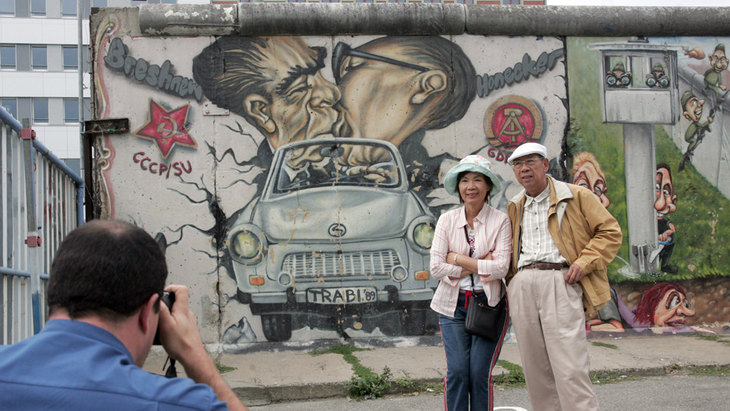 Touristen lassen sich vor der East-Side-Gallery fotografieren