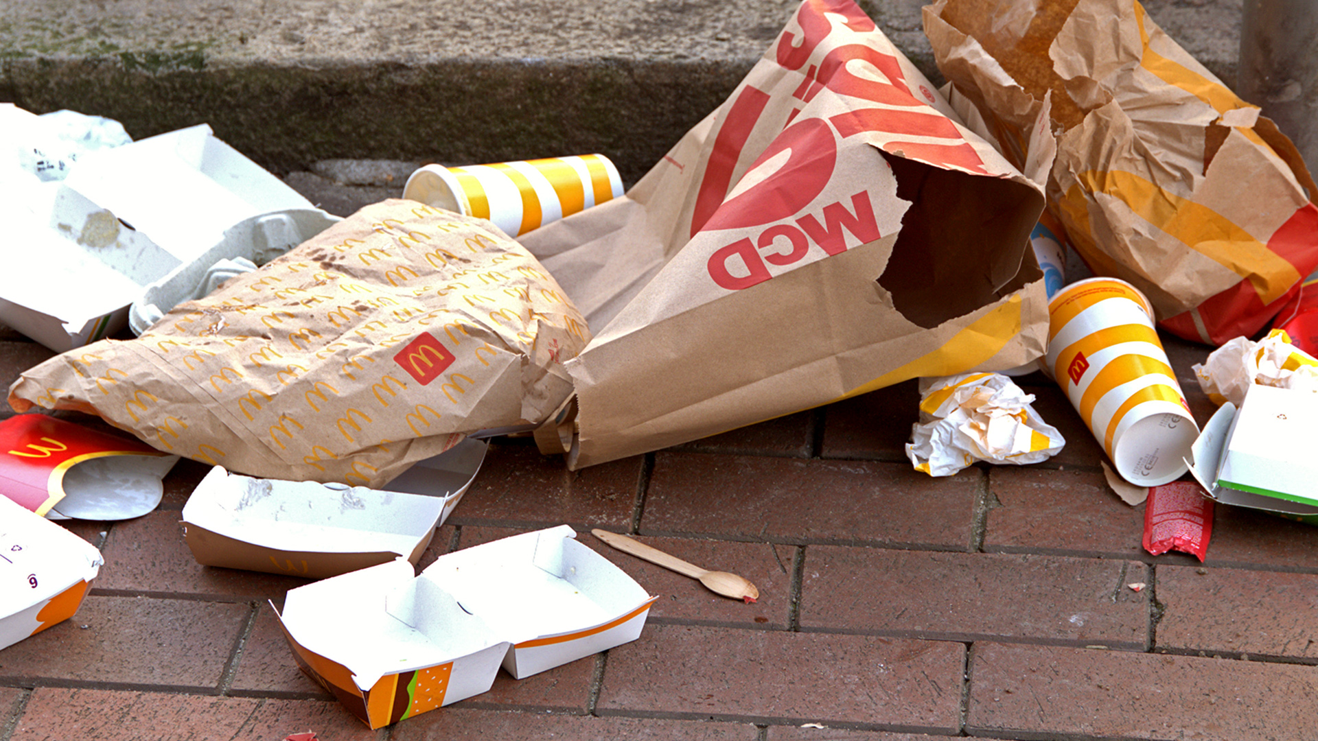 Diverse McDonalds-Verpackungen liegen auf dem Boden in einer Fußgängerzone. | picture alliance / SULUPRESS.DE