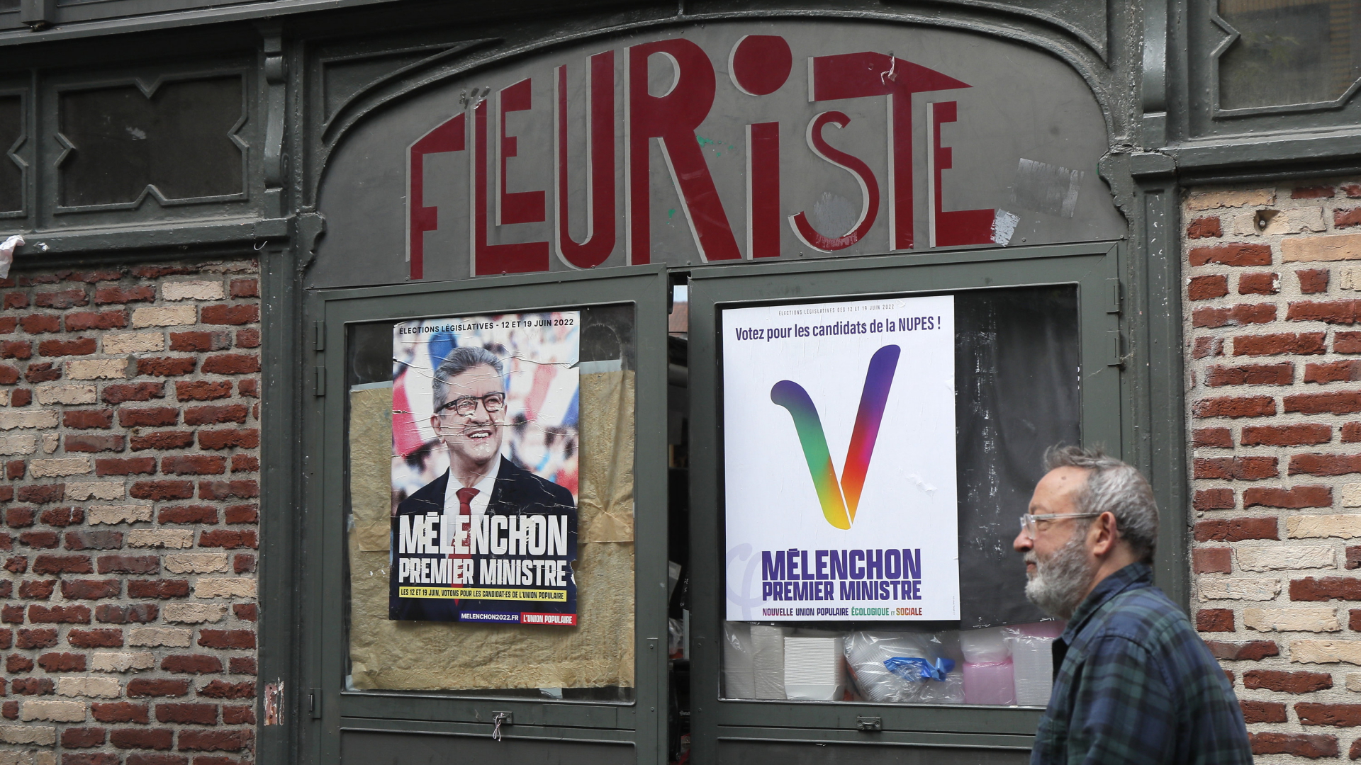 Ein Mann geht an Wahlplakaten von Melenchons NUPES vorbei.