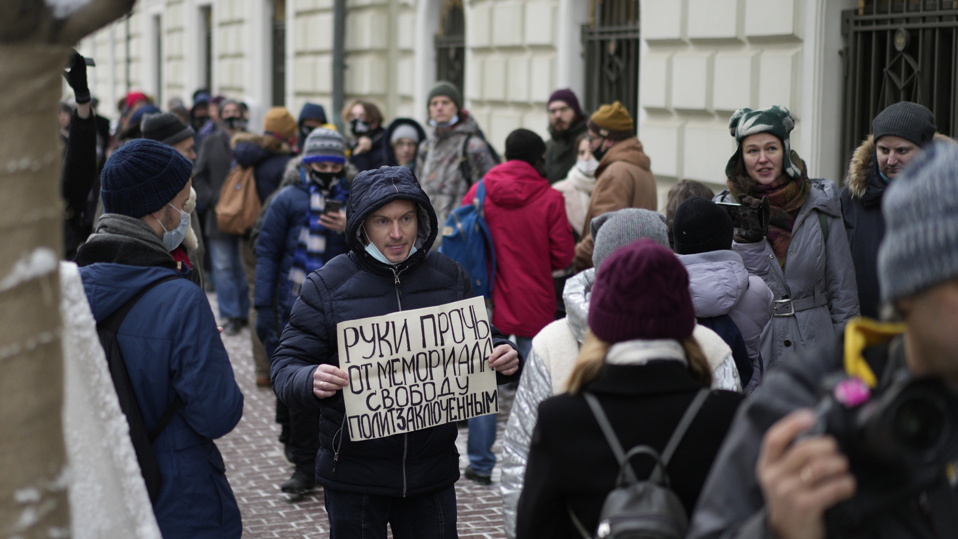 Ein Demonstrant hält ein russisches Plakat mit der Aufschrift "Hände weg von Memorial, Freiheit für politische Gefangene" hoch.  | picture alliance/dpa/AP