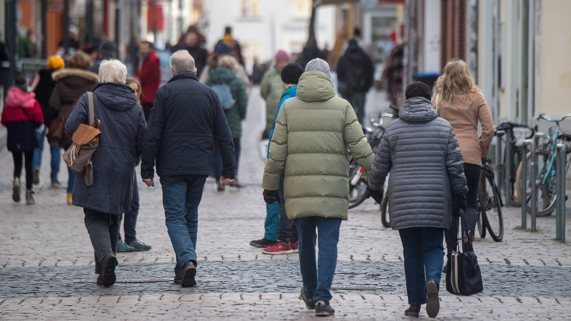 Menschen gehen in Greifswald eine Füßgängerzone entlang. | dpa