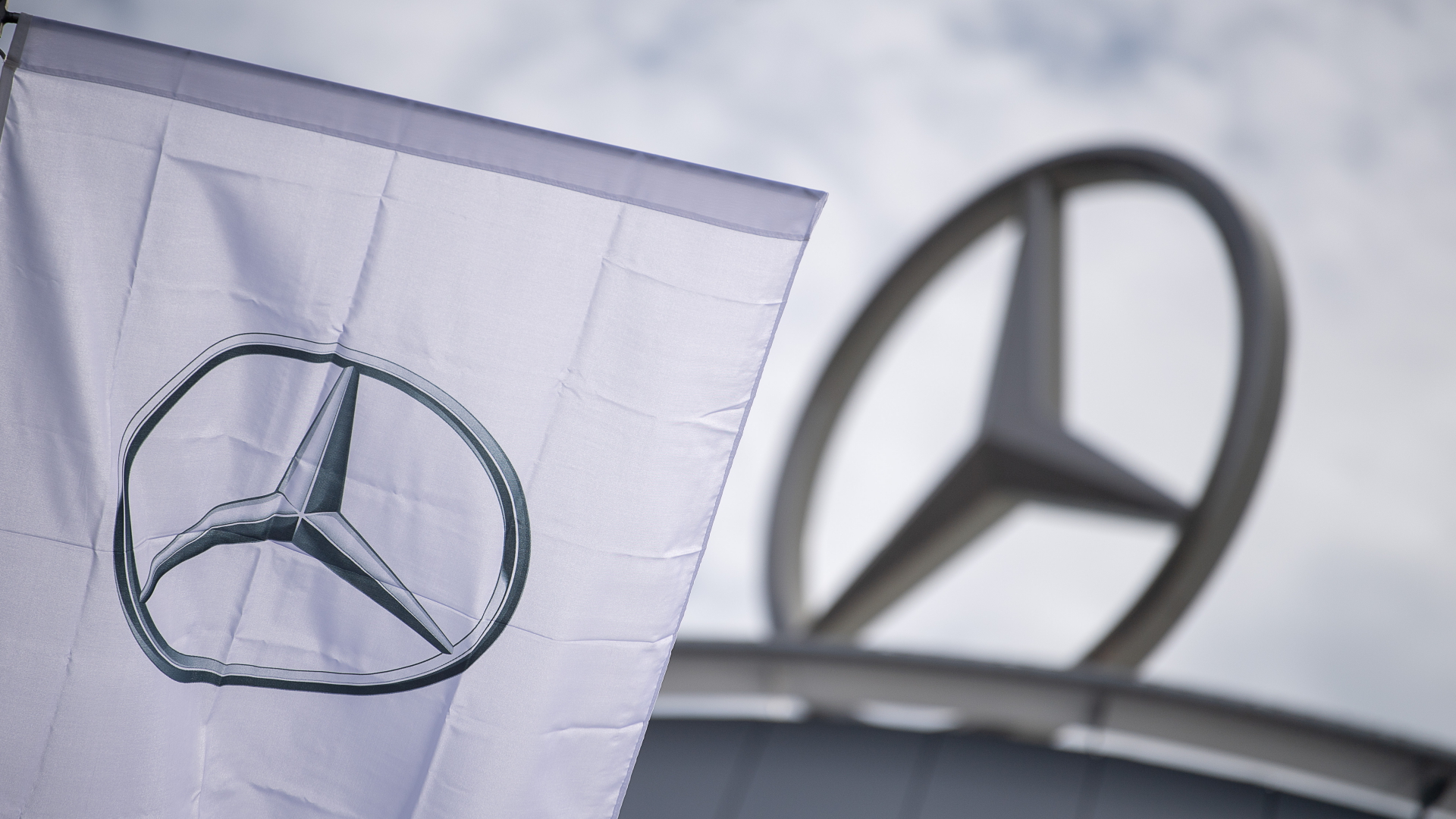 Eine Fahne mit dem Logo des Autoherstellers Mercedes-Benz weht vor einem Showroom der Firma. | dpa