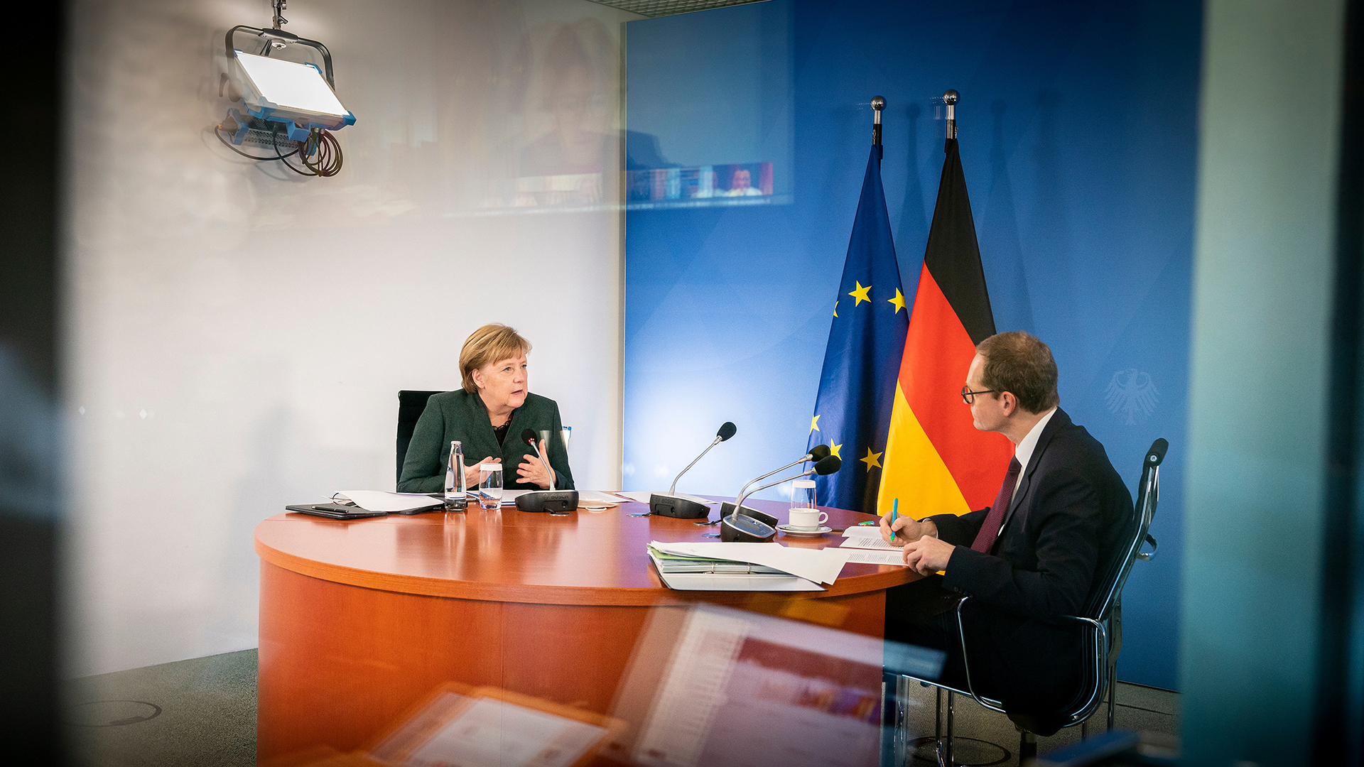 Angela Merkel und Michael Müller sitzen an einem Tisch während der Videokonferenz mit den Ministerpräsidenten
