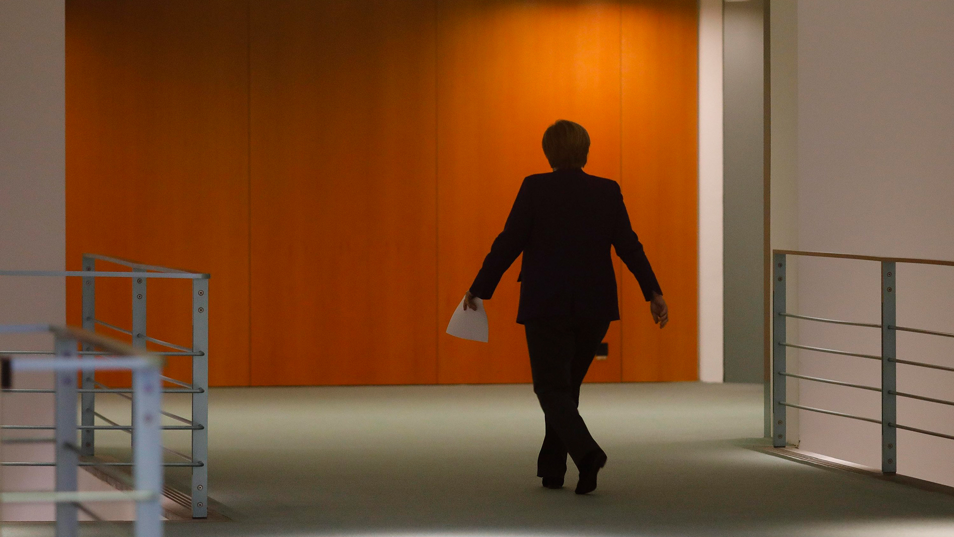 Angela Merkel geht einen Flur entlang. | AP