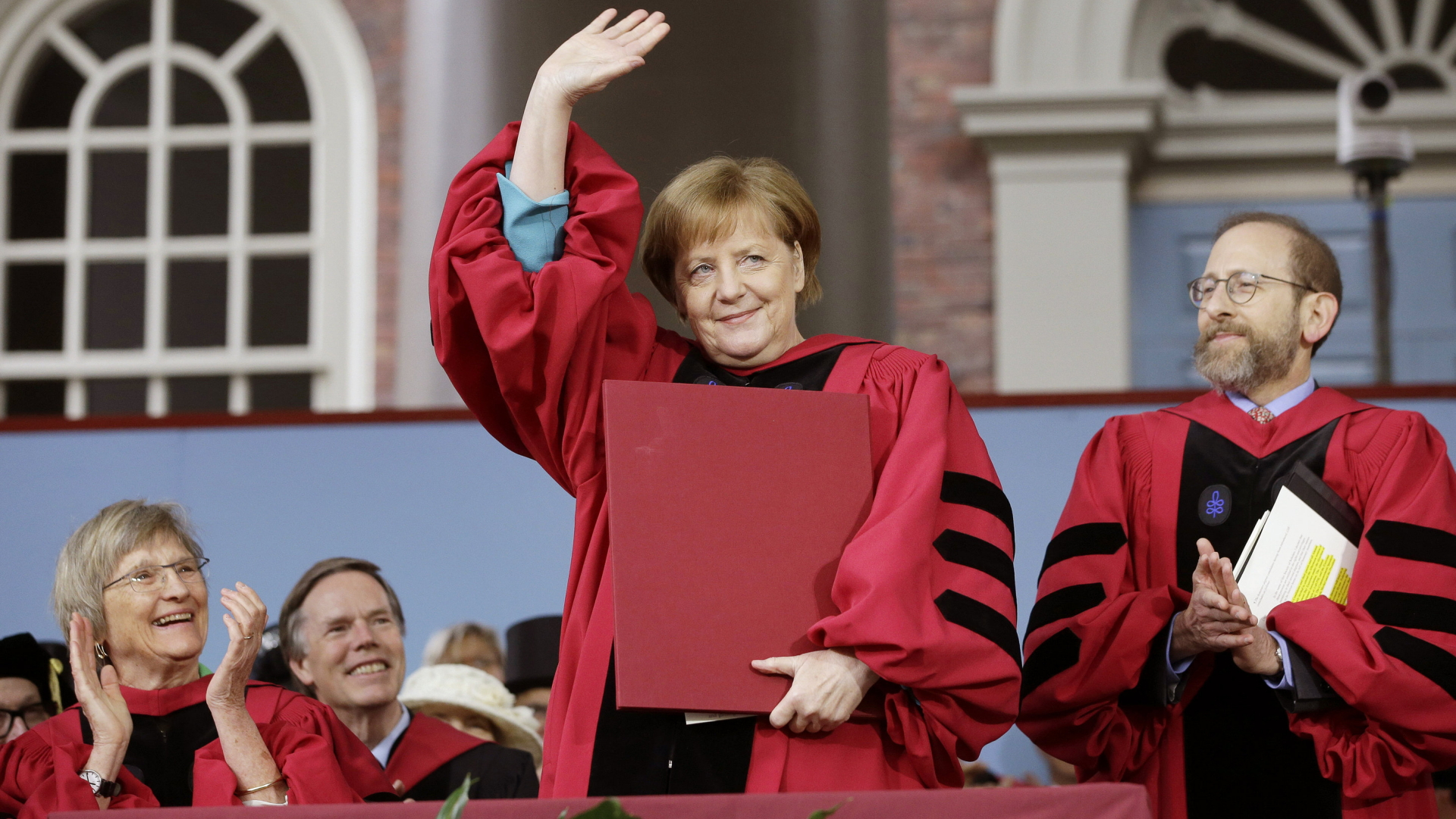 Angela Merkel winkt an der Harvard-Universität in Cambridge dem Publikum zu. | dpa