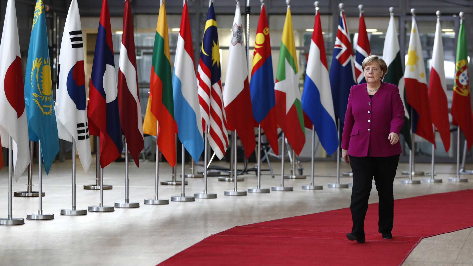Bundeskanzlerin Angela Merkel schreitet bei der Ankunft zum Asem-Treffen in Brüssel die Nationalflaggen entlang. | Bildquelle: dpa