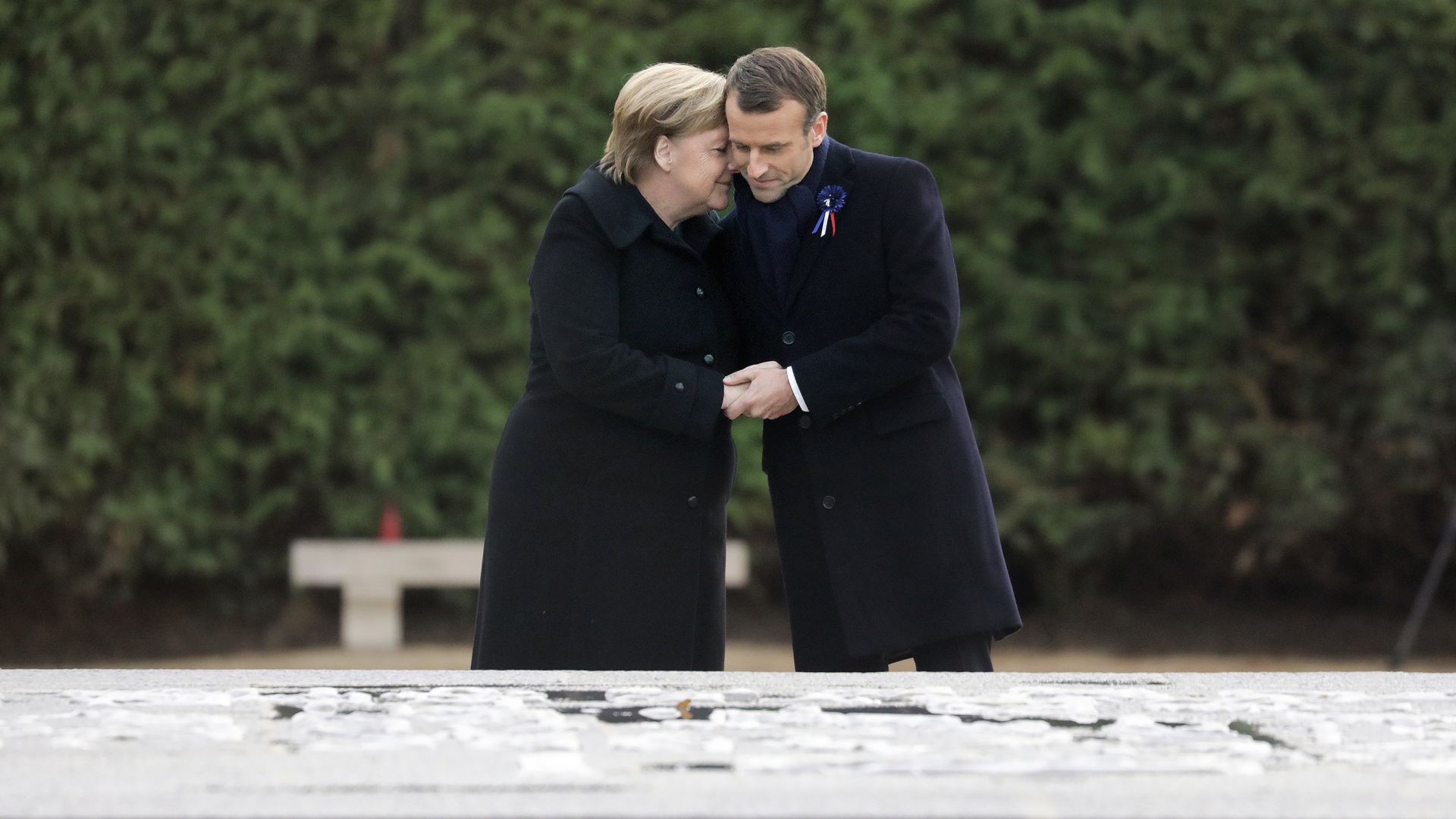 Kanzlerin Merkel und Frankreichs Präsident Macron halten sich an der Gedenkstätte in Compiègne im Arm. | Bildquelle: dpa