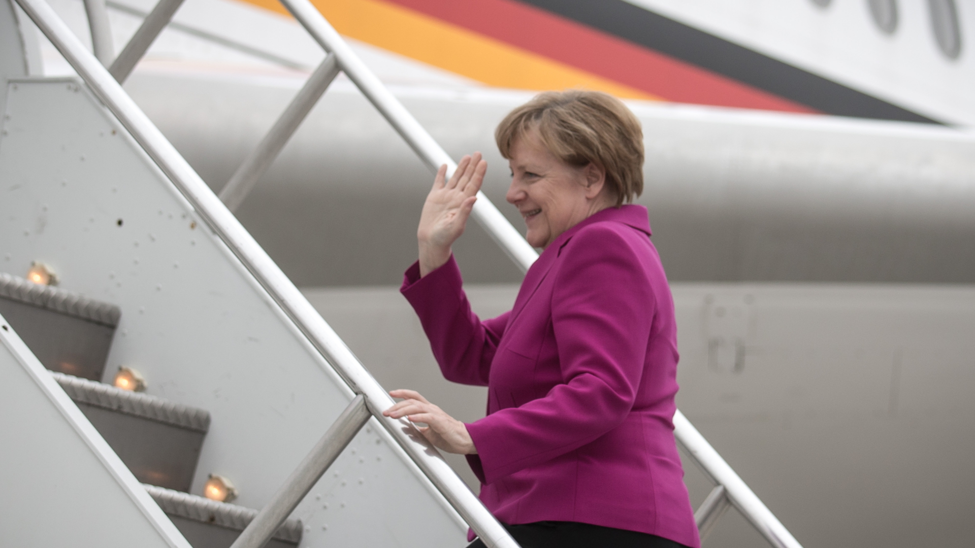 Angela Merkel steigt winkend in ein Flugzeug der Luftwaffe. (Archivbild) | dpa