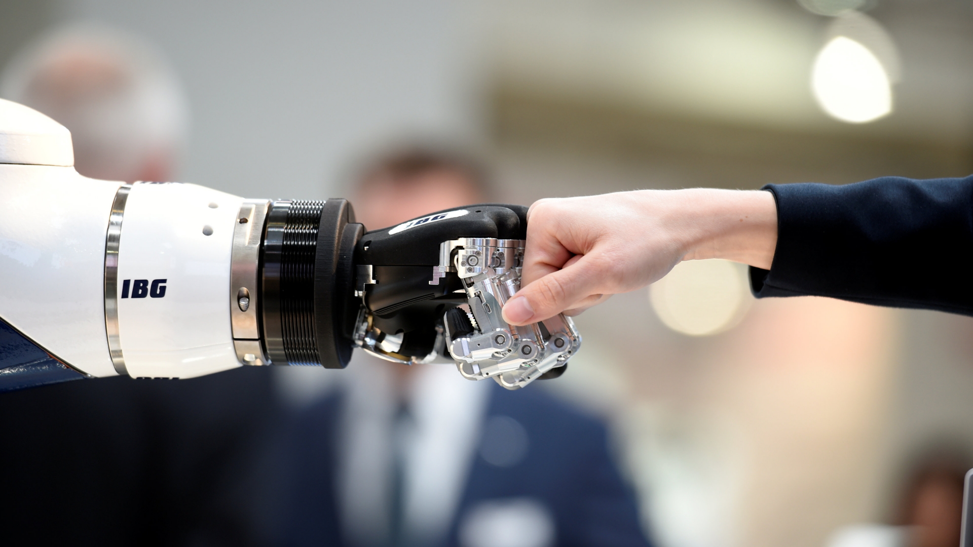 Ein Besucher reicht einem Roboterarm auf der Hannover Messe die Faust zum Gruß. | REUTERS