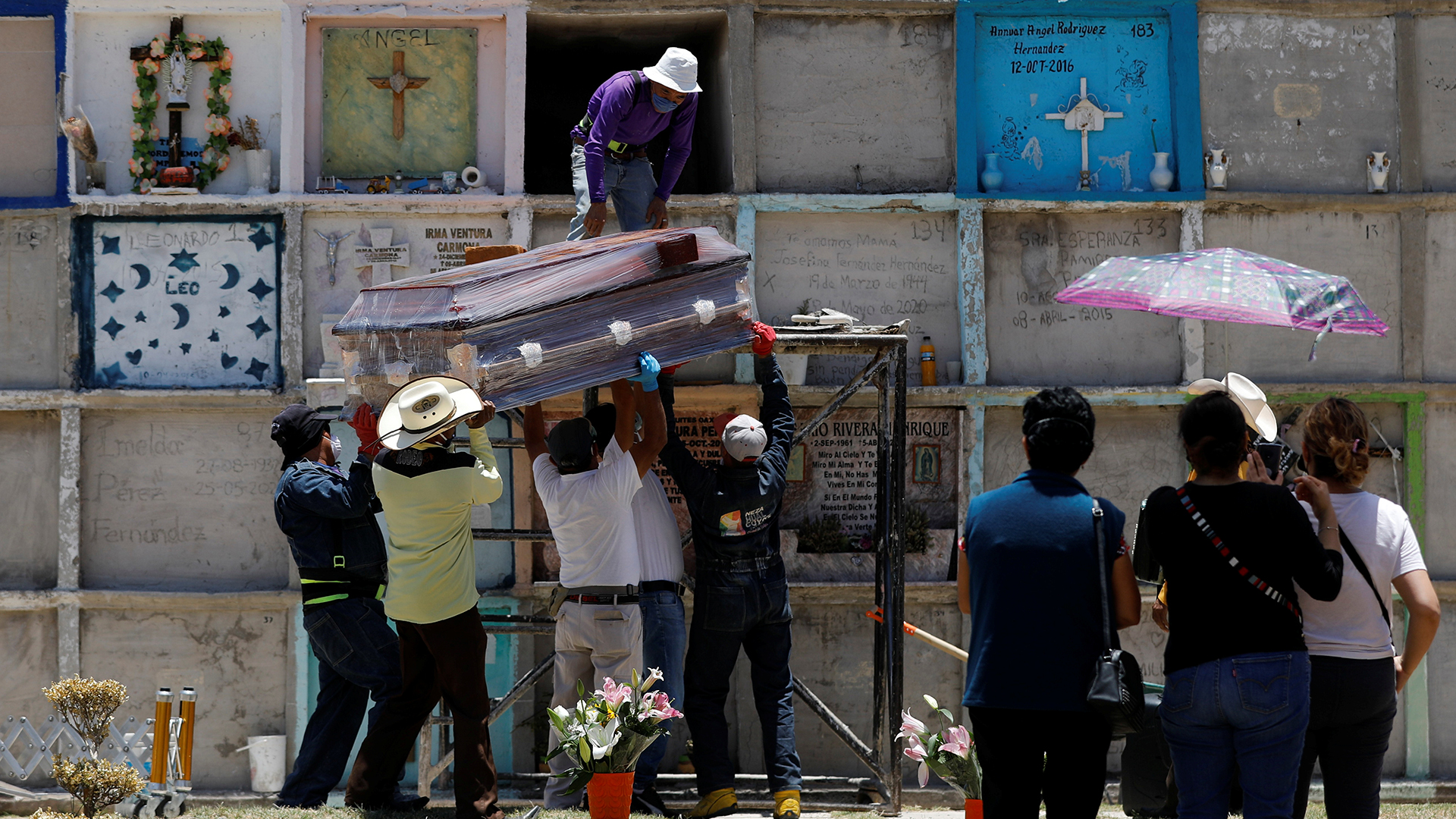 Friedhofsmitarbeiter im mexikanischen Nezahualcoyotl heben einen Sarg in ein Grab. 