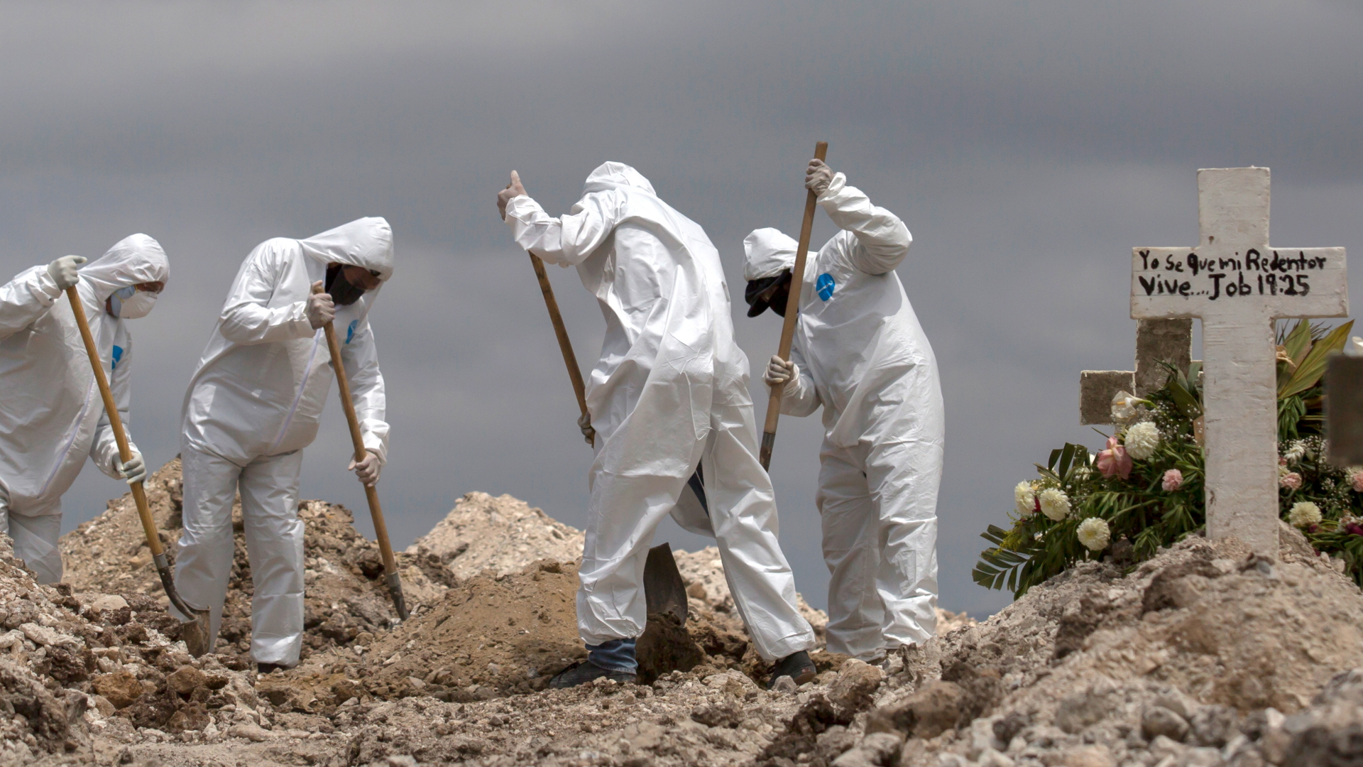 Tijuana: Arbeiter in Schutzanzüge schaufeln Erde bei einer Beerdigung im Rahmen der Covid-19-Pandemie. | Bildquelle: dpa