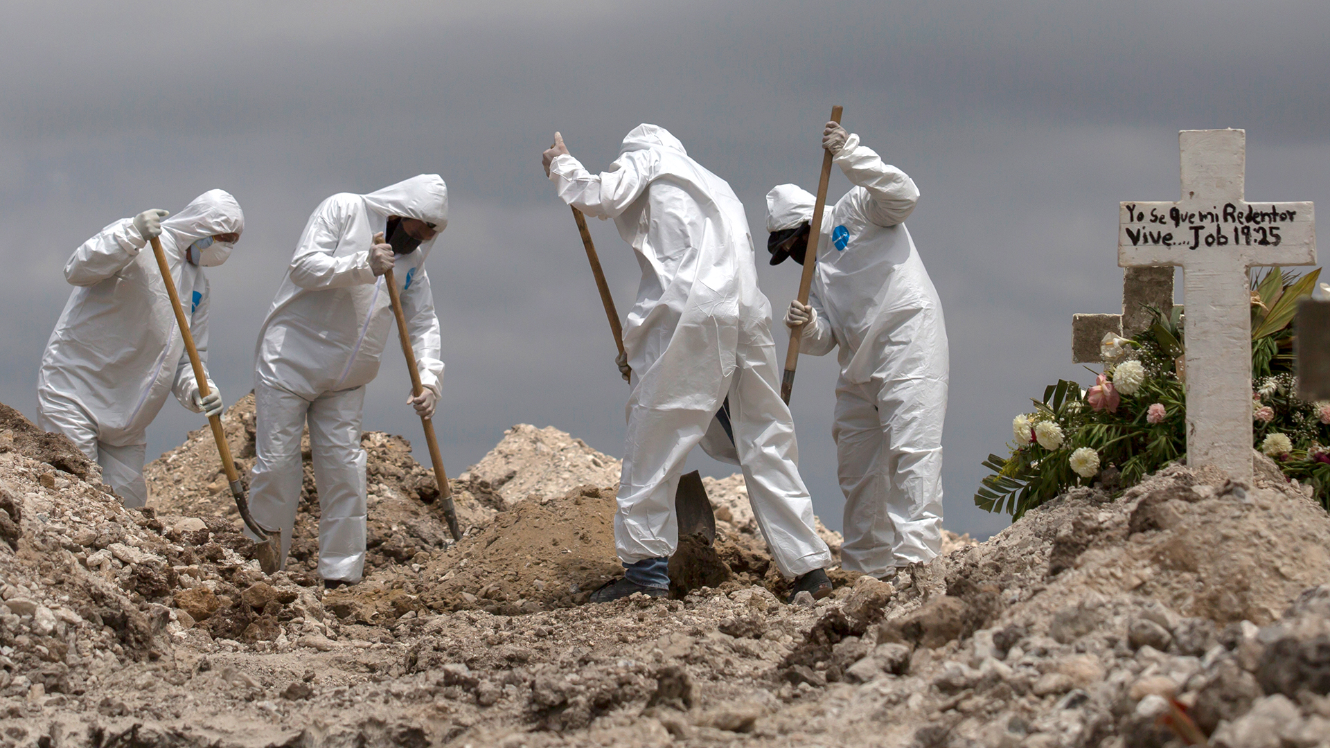 Arbeiter in Schutzanzüge schaufeln Erde bei einer Beerdigung im Rahmen der Covid-19-Pandemie | Bildquelle: dpa
