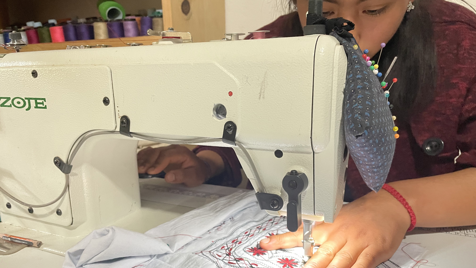 Eine Näherin stickt mit der Maschine ein traditionelles Muster auf eine Bluse. | Jenny Barke