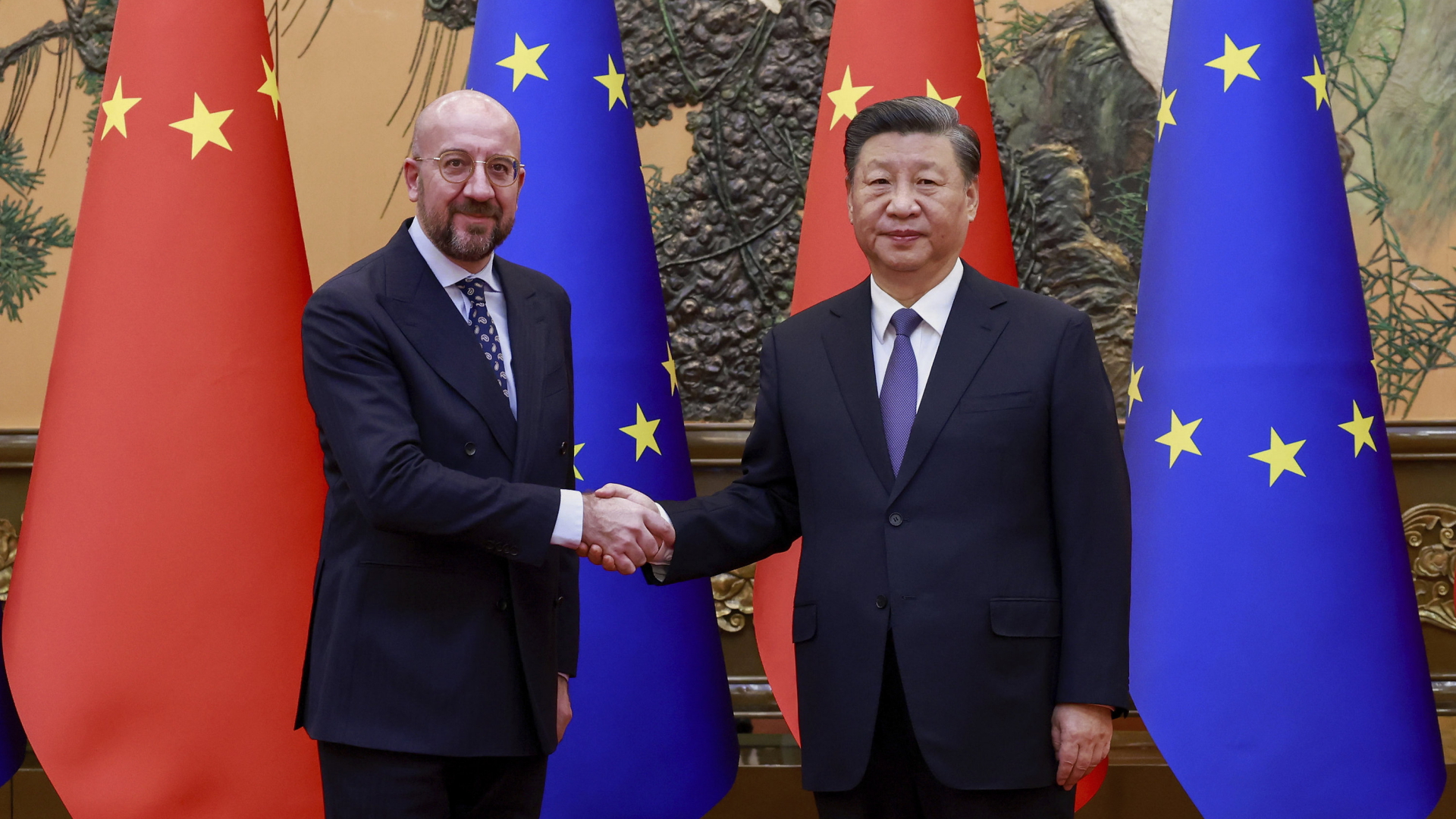 Charles Michel und Xi Jinping schütteln sich bei einem Treffen in Peking die Hand, dahinter stehen Flaggen der EU und Chinas.  | AP