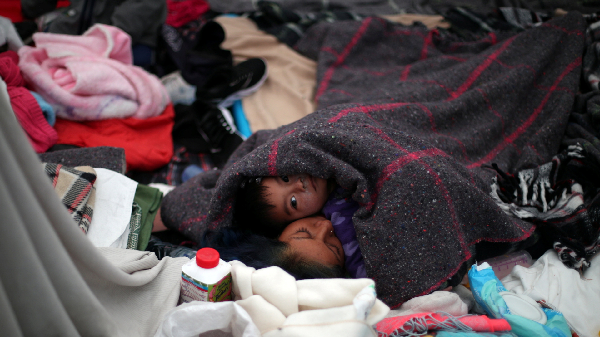 Kinder liegen in Wolldecken gehüllt auf dem Boden. | Bildquelle: REUTERS