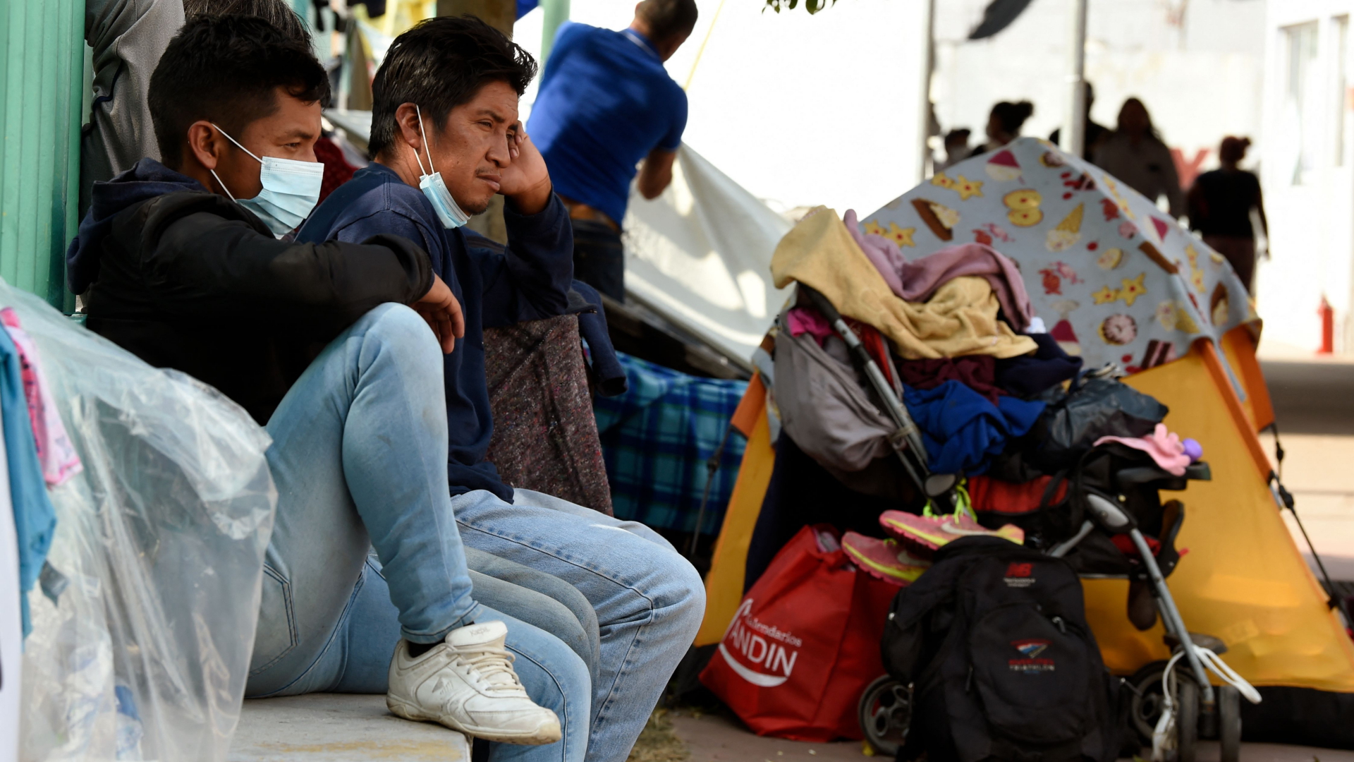 Migranten sitzen neben ihren Habseligkeiten auf einer Steinmauer in Mexiko-Stadt. | AFP