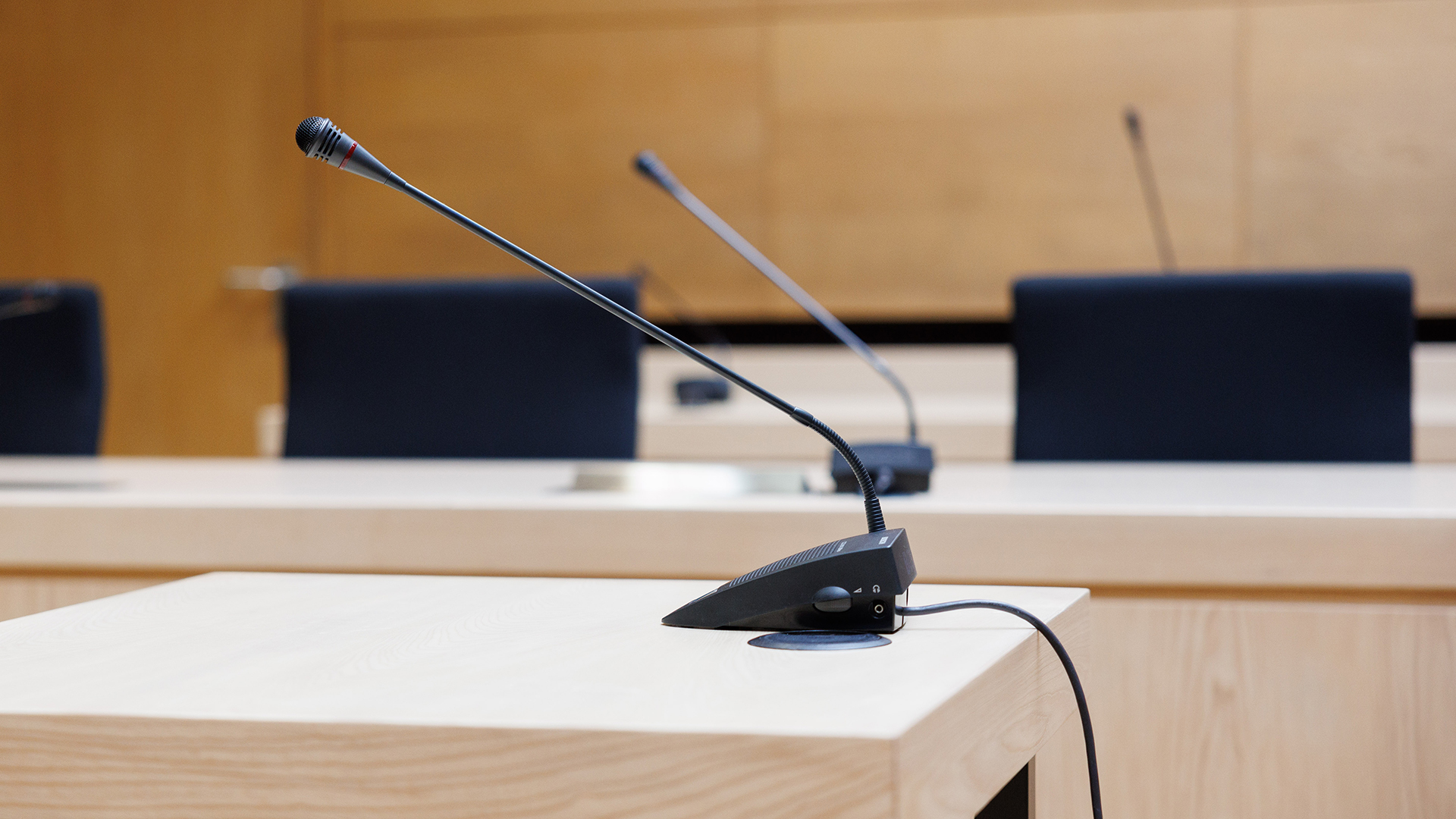 Tischmikrofone stehen in einem Gerichtssaal eines Landgerichts.