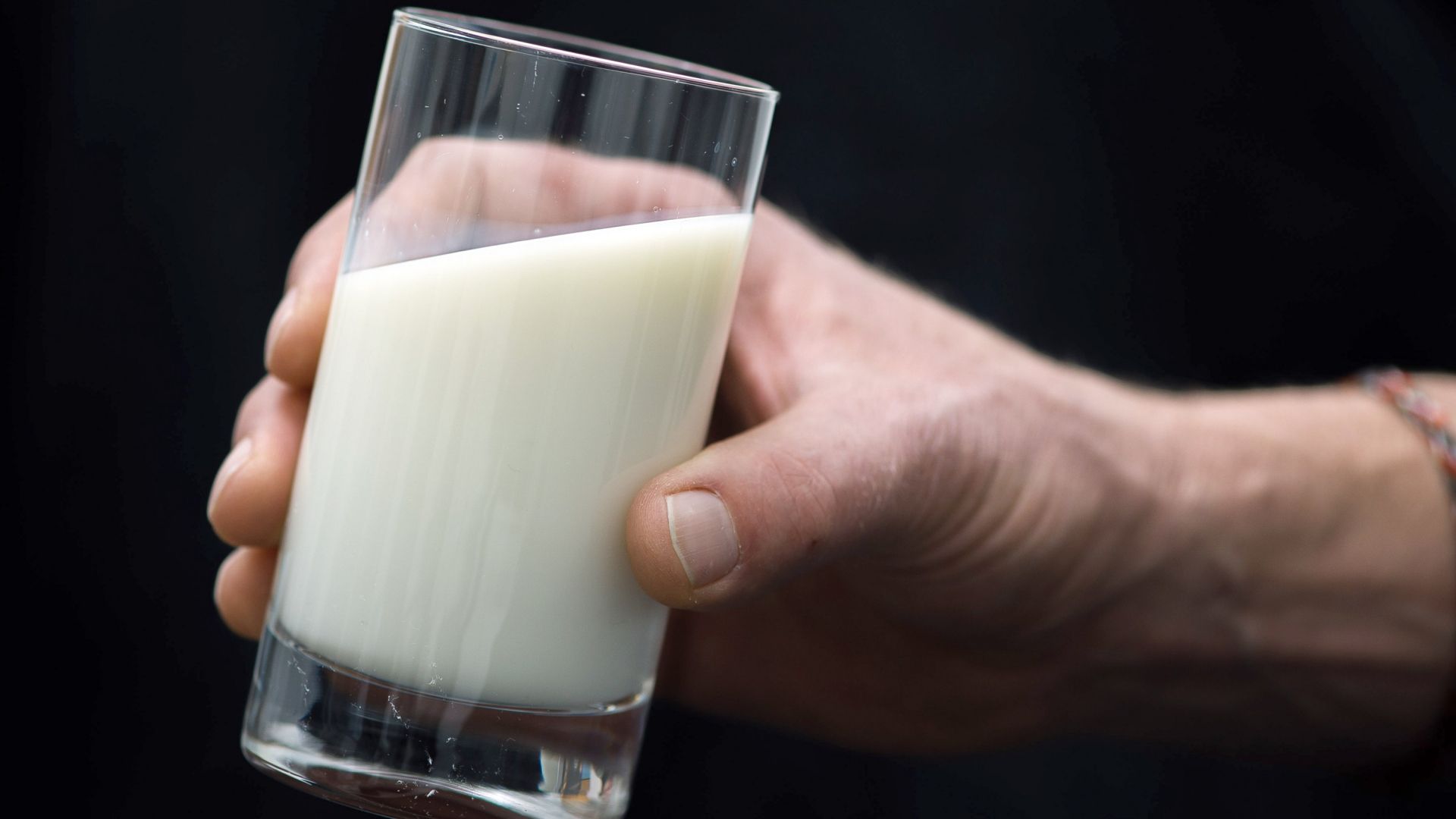 Eine Hand hält ein Glas mit Milch. | dpa
