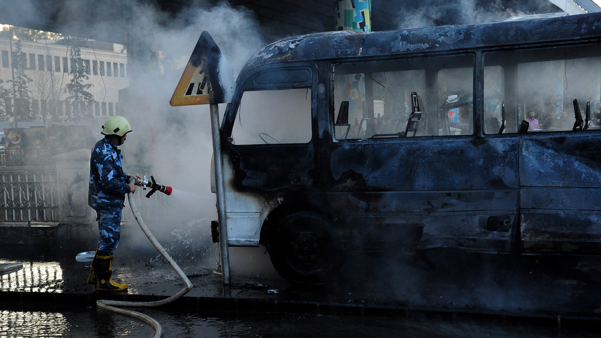 Ein Soldat löscht einen ausgebrannten Militärbus in der syrischen Hauptstadt Damaskus. | via REUTERS