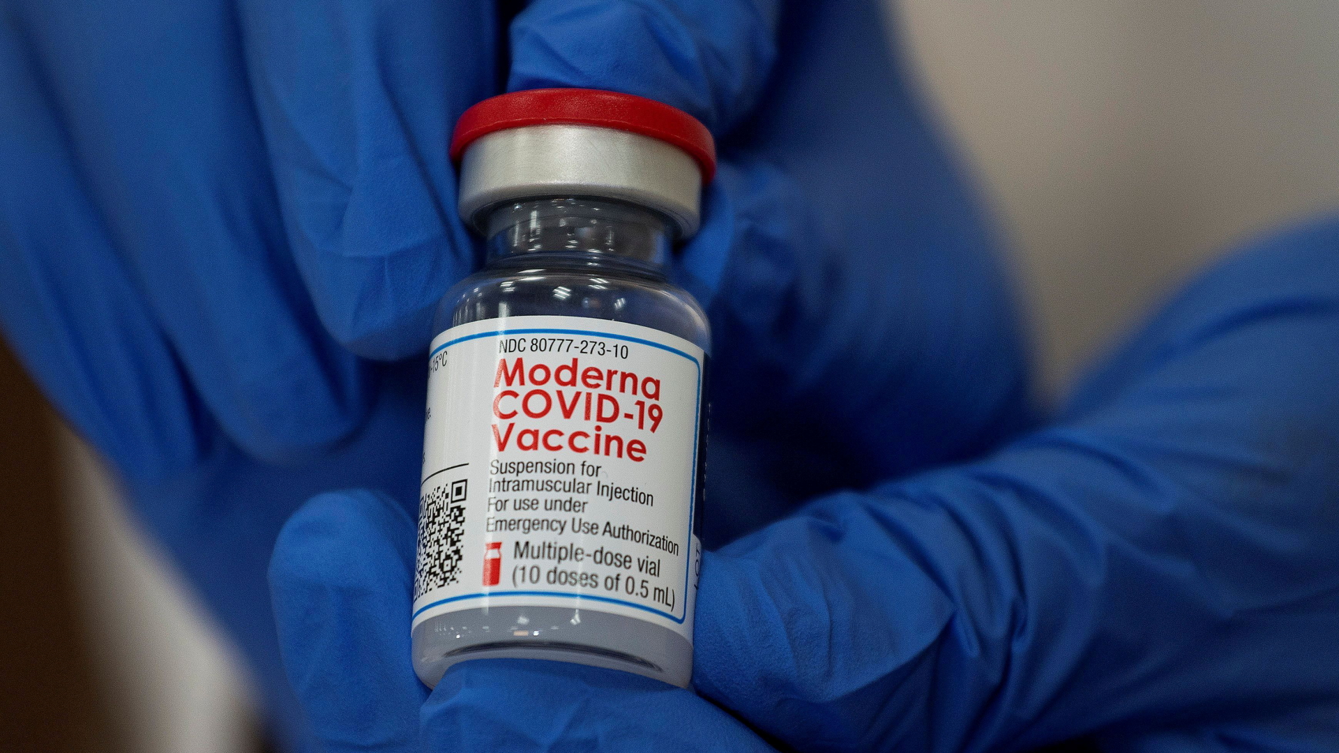 Ein Mitarbeiter hält ein Fläschchen des Moderna-Impfstoffs in der Hand. | REUTERS