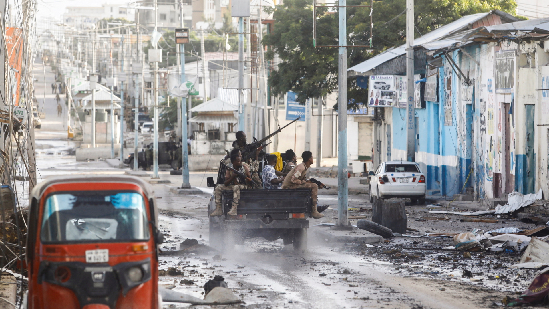 Bewaffnete Somalische Sicherheitskräfte fahren in einem Pickup an einem Gebäudeteil des belagerten Hotels in Mogadischu vorbei. | REUTERS