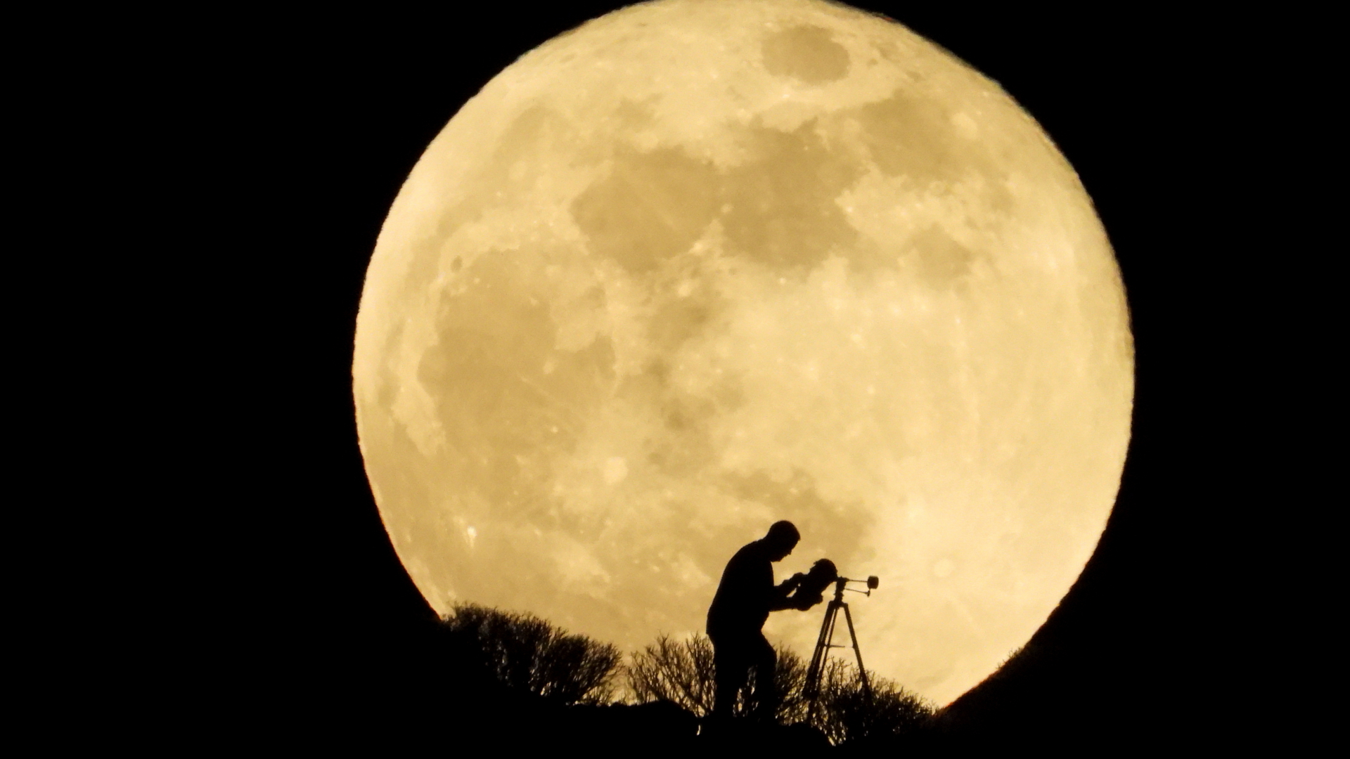 Ein Mann mit einem Teleskop vor dem Supermond auf Gran Canaria | REUTERS