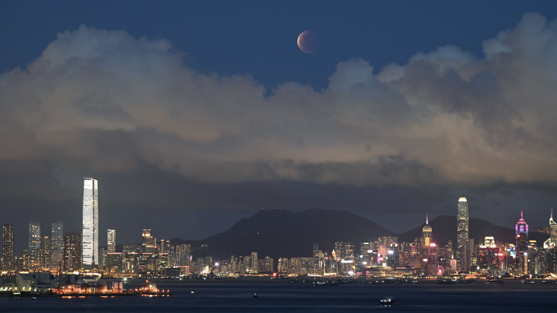Ein Supermond steht während einer Mondfinsternis am Himmel geht über dem Victoria Harbour in Hongkong auf. | dpa