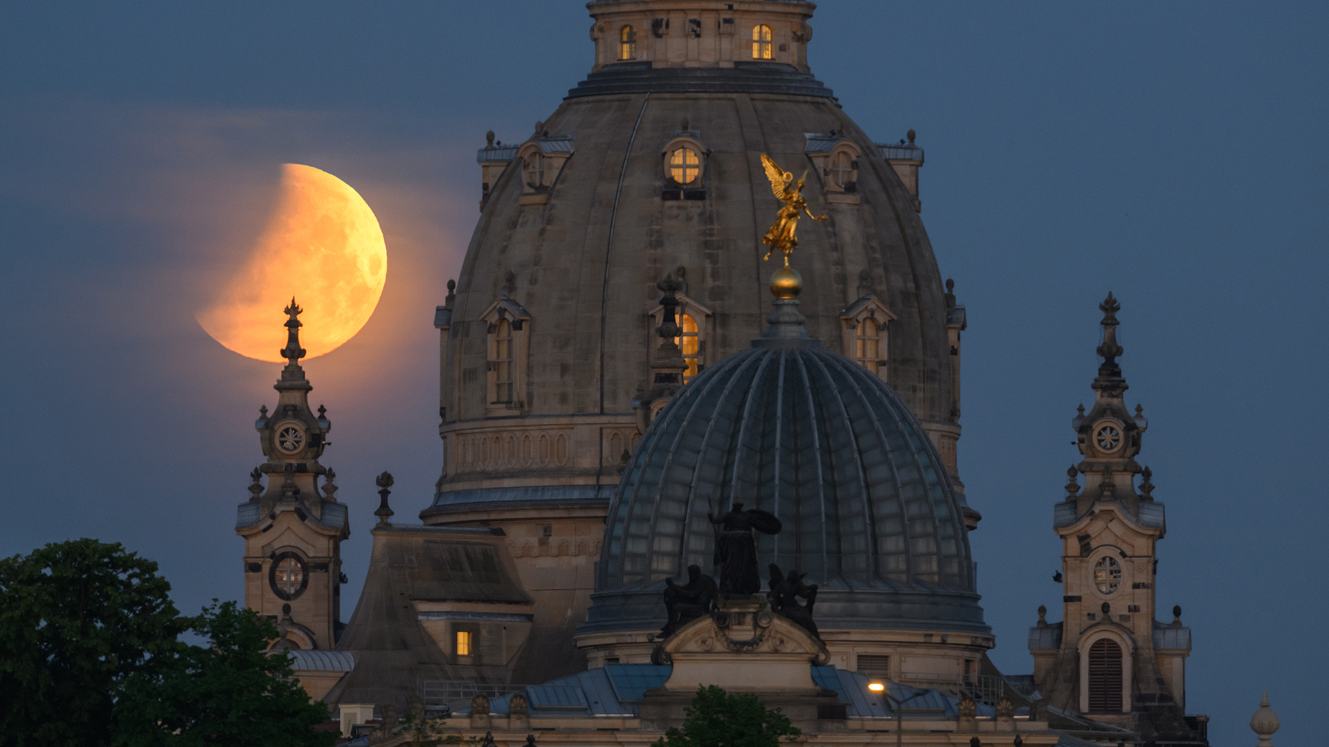 In Dresden (Sachsen) geht der Mond am Morgen während einer partiellen Mondfinsternis hinter der Frauenkirche und der Kuppel der Kunstakademie mit dem Engel "Fama" unter. | dpa