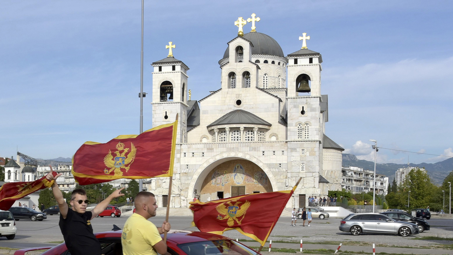 Anhänger der Regierungspartei Montenegros schwenken Flaggen vor einer orthodoxen Kirche. | AP