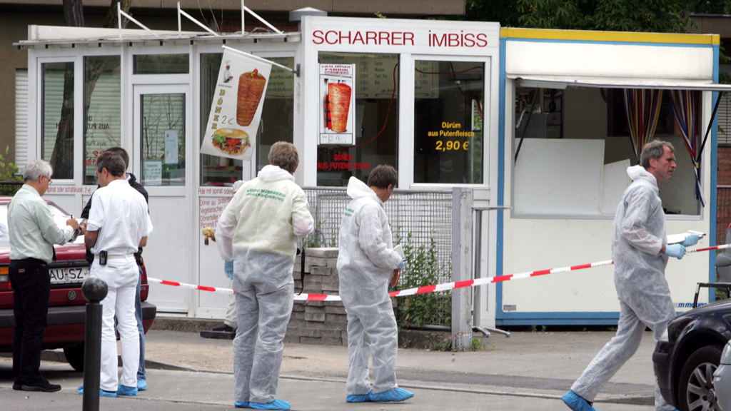 Polizisten der Spurensicherung in weißen Schutzanzügen arbeiten an einem Imbiss in Nürnberg, dessen Besitzer im Juni 2005 erschossen wurde.