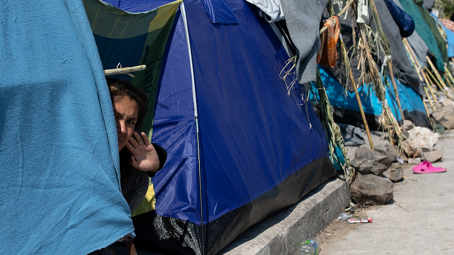 Eine Frau guckt in Moria auf Lesbos aus einem Zelt | Bildquelle: REUTERS