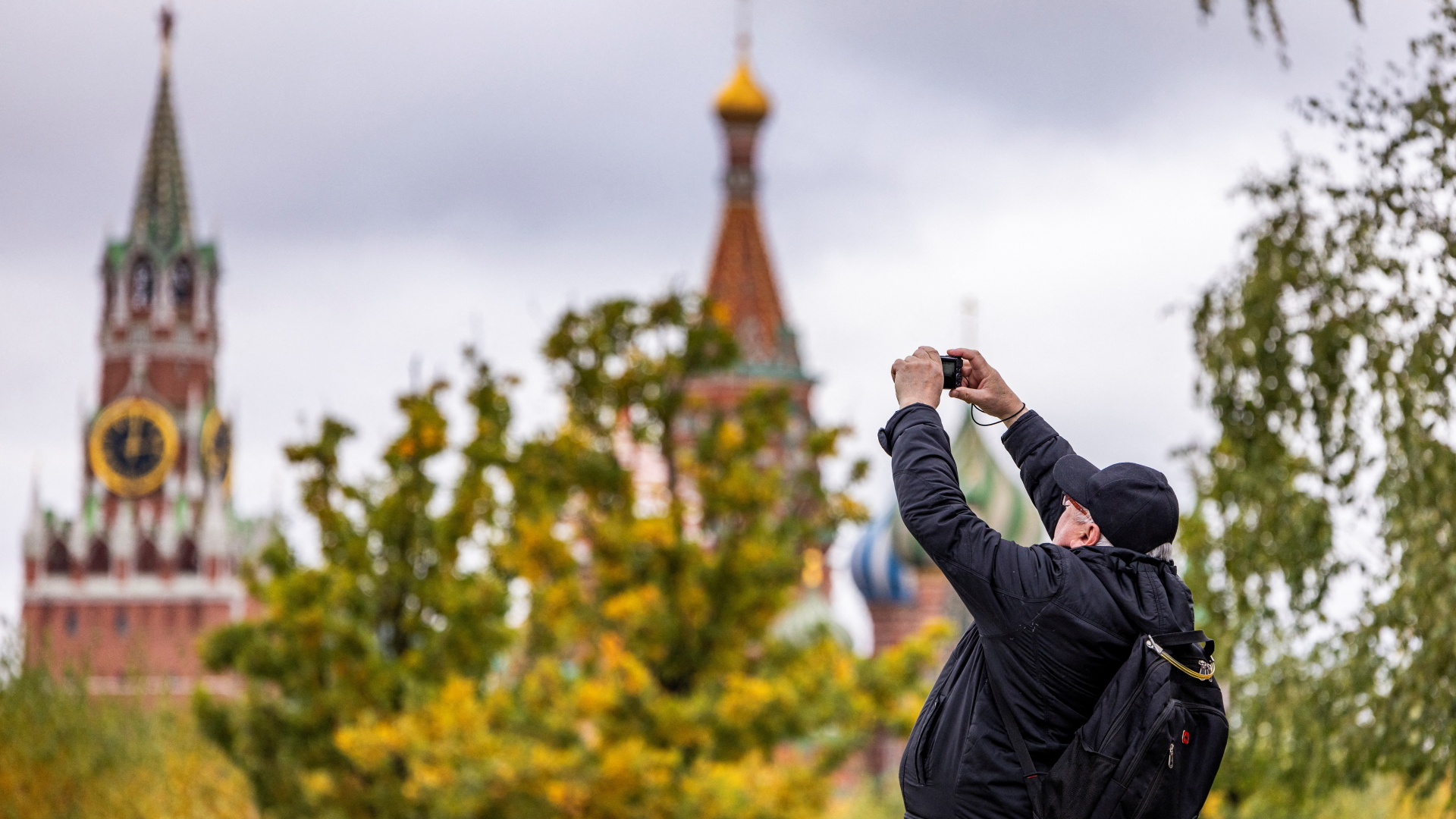 Ein Mann fotografiert zwei Kremltürme mit einer Handkamera.