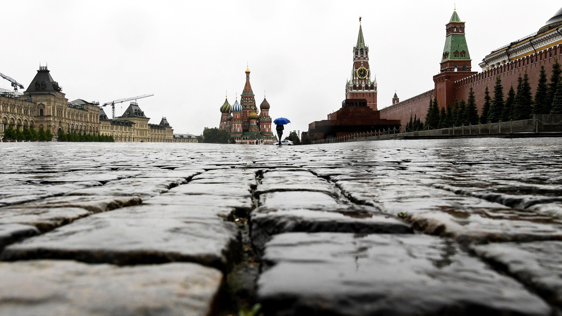 Ein Mann mit einem Regenschirm geht über den Roten Platz. | AFP
