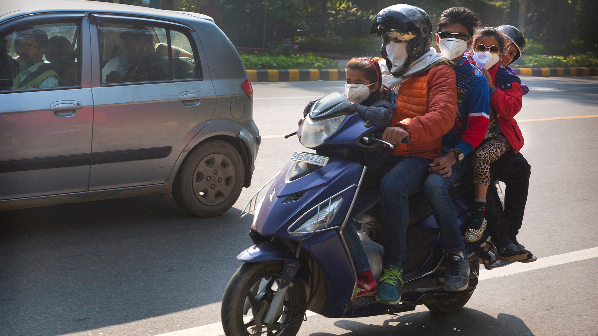 Eine Familie fährt auf einem Roller mit Schutzmasken durch Neu-Delhi.  | AP