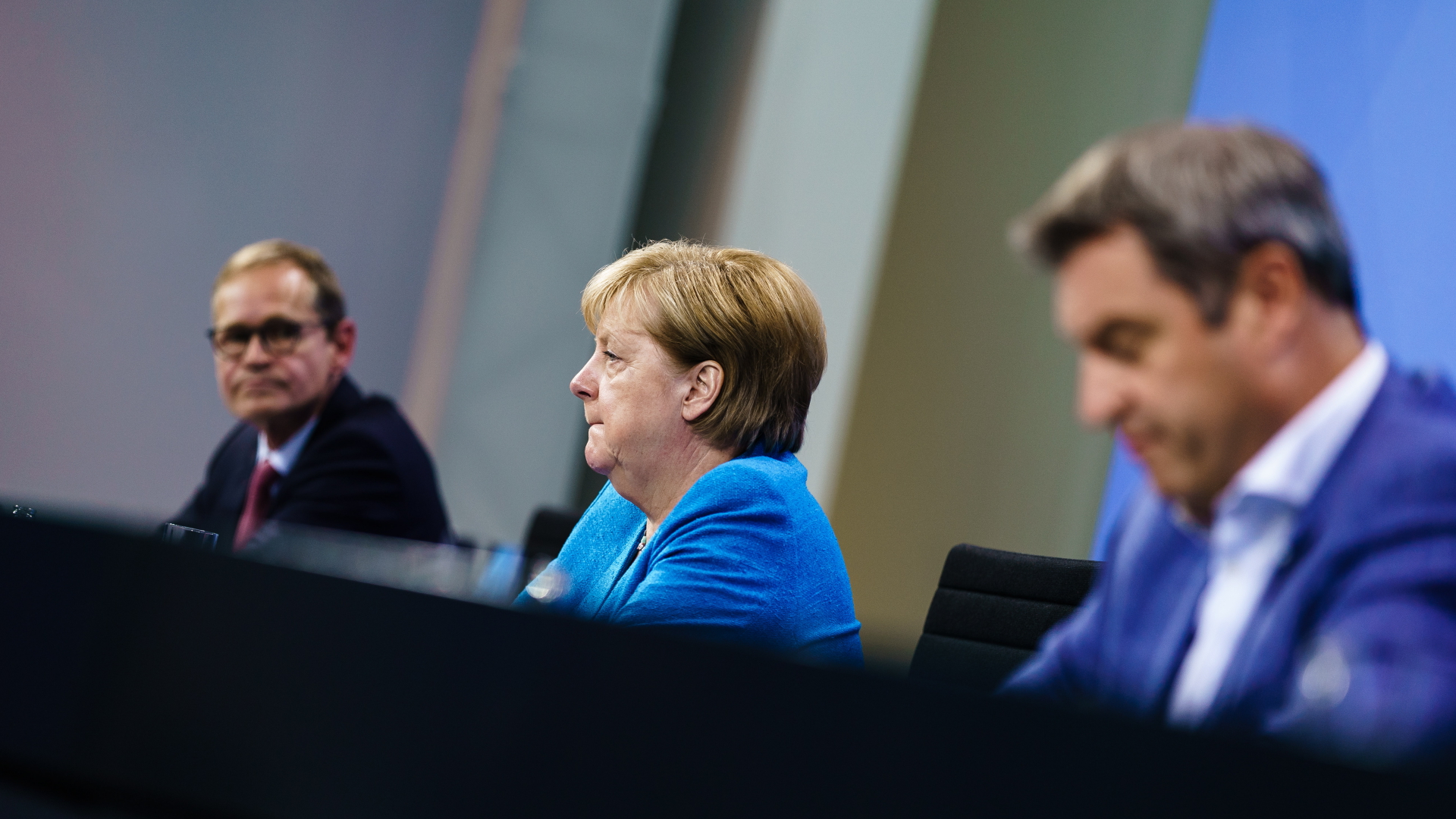 Michael Müller, Angela Merkel und Markus Söder sitzen nebeneinander auf einer Pressekonferenz nach dem Bund-Länder-Treffen.