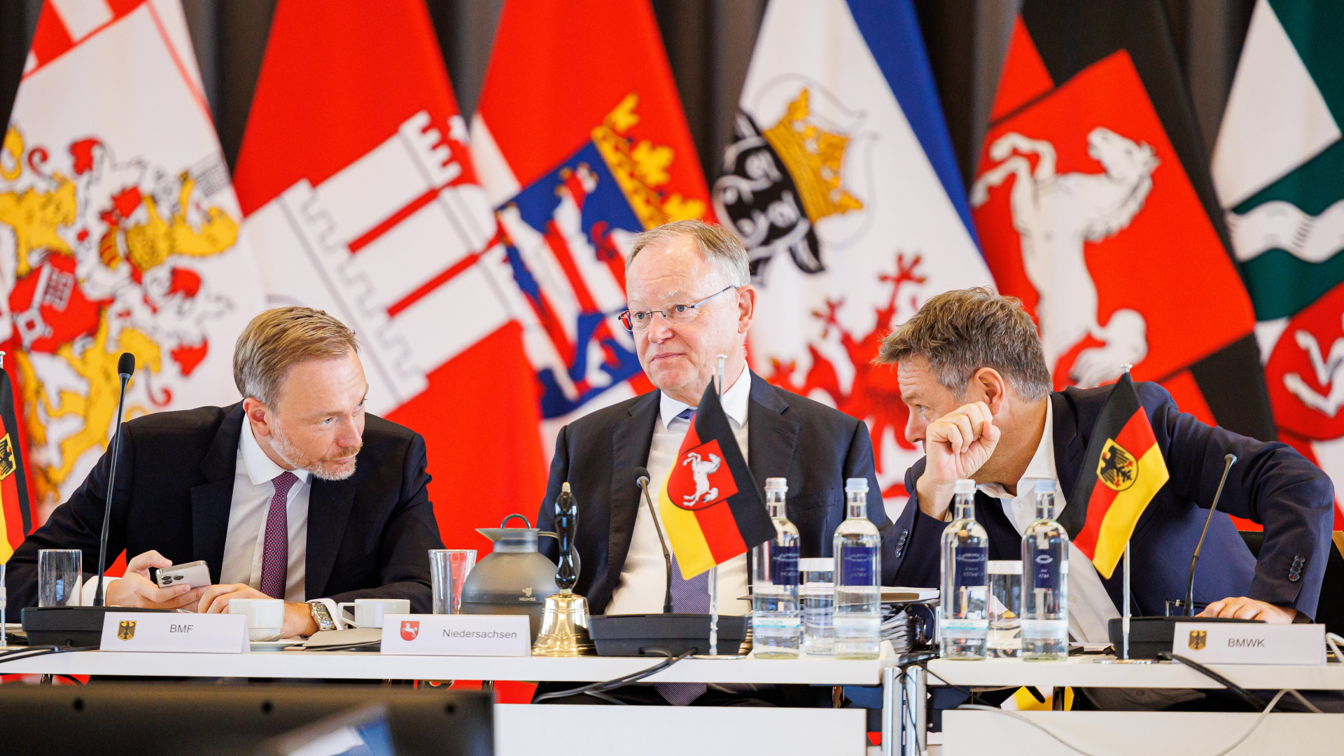 Christian Lindner, Stephan Weil und Robert Habeck sitzen bei der Ministerpräsidentenkonferenz vor Flaggen der Bundesländer | dpa
