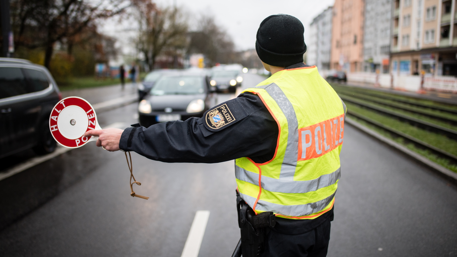 Ein Polizist stoppt in München an einer Kontrollstelle ein Fahrzeug. | dpa